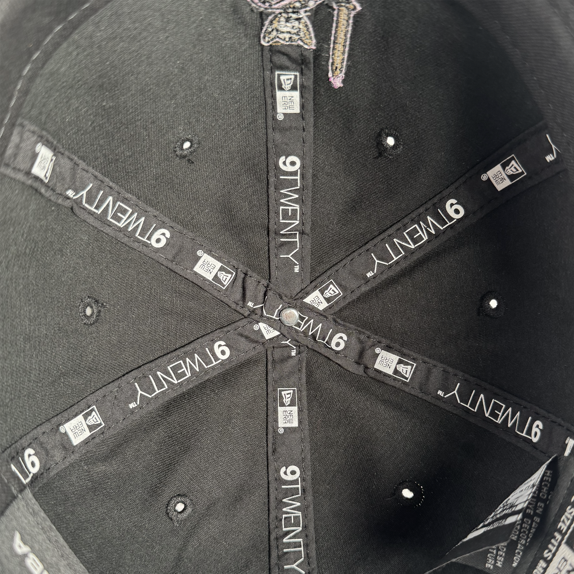 Close-up of the inside of a black GSV 9TWENTY Dad hat by GSV, featuring stitched black fabric strips labeled “9TWENTY” and “GSV” in white text, with small ventilation holes and intersecting threads at the center.