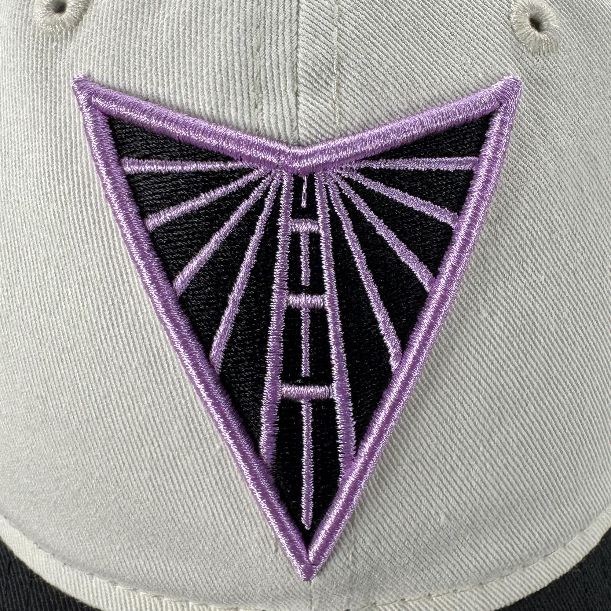 A close-up of the GSV Logo 2 9TWENTY Hat by GSV shows an embroidered emblem—a downward-pointing triangle with purple rays—adding modern flair. The adjustable strap back ensures comfort, inspired by the spirit of the Golden State Valkyries.