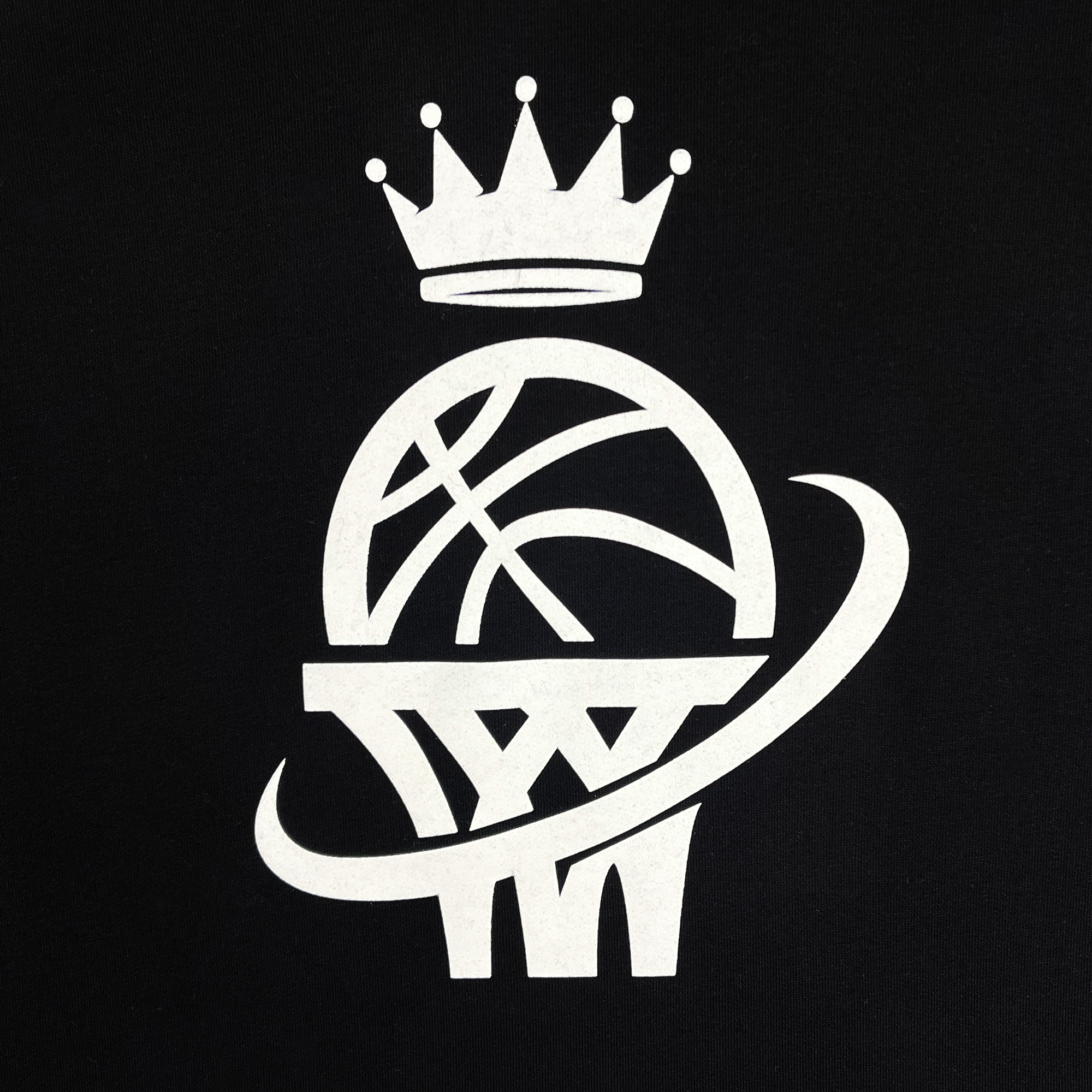 The WPBA Core Hoodie's logo displays a white basketball intersected by two navy blue lines, resting above a hoop and encircled by a pointed curved line. Above the ball, there is a five-pointed crown. This emblem, set against a black background, represents the Women's Premier Basketball Association and women's sports empowerment. The hoodie is crafted by the brand Oaklandish.
