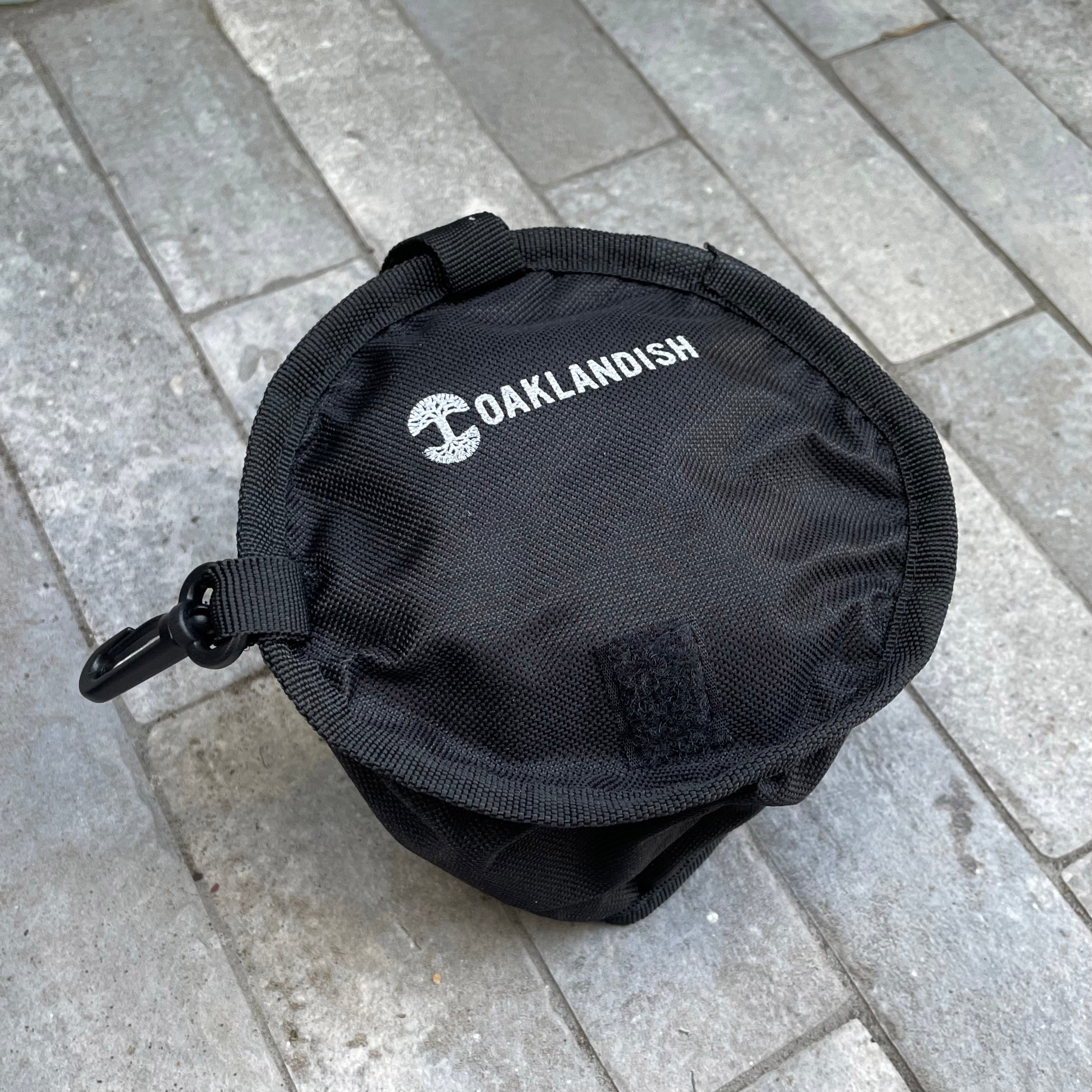 Tope view of black pet travel water bowl with white Oaklandish wordmark and tree logo on the top.