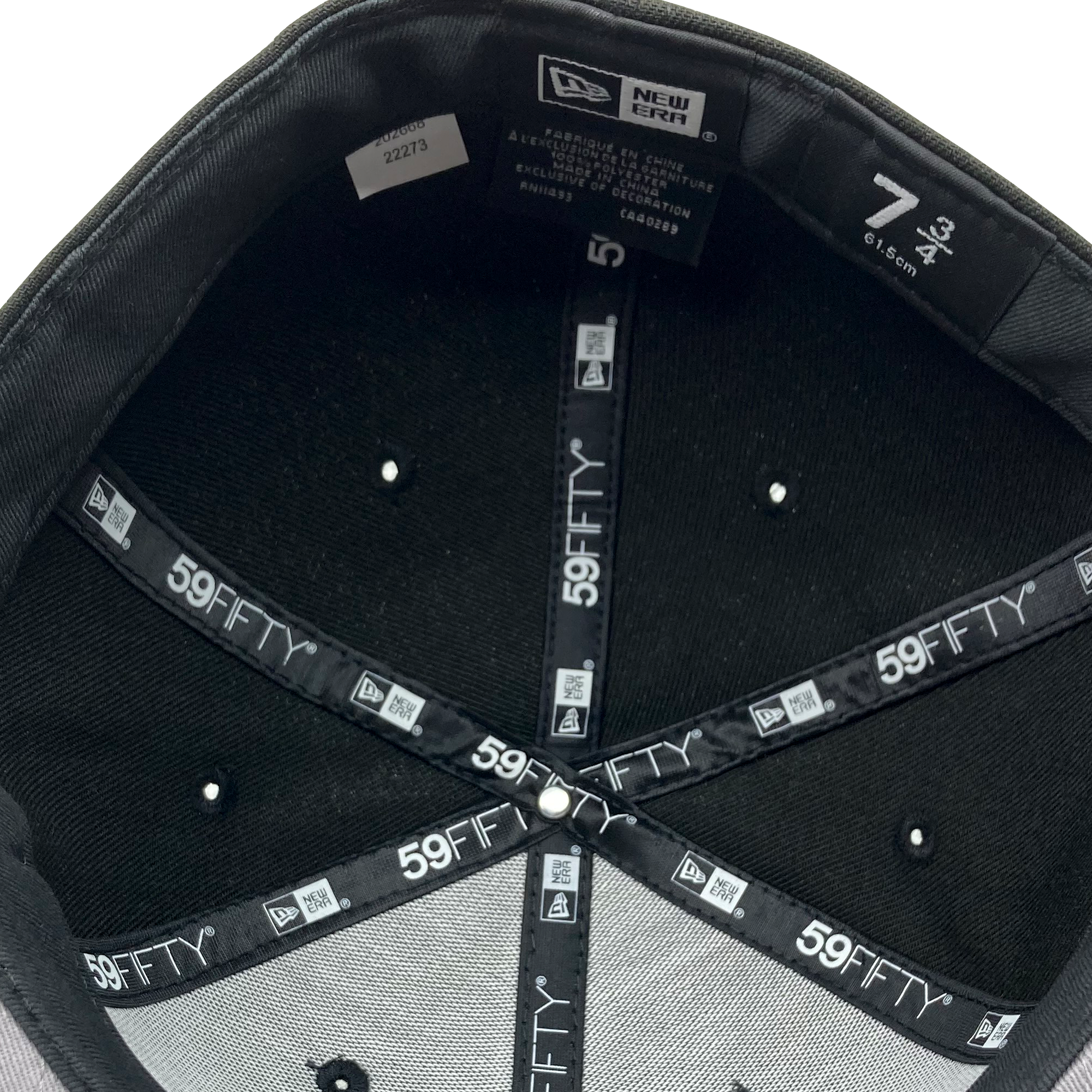 Interior view of a black New Era Hiero 59FIFTY Fitted Cap by Hieroglyphics, showcasing the branded tapes with "59FIFTY" printed in white letters against a black background. The size label indicates it's a size 7 3/4, 61.5 cm. Tags display manufacturing details and product information, while six monochrome eyelets are visible.