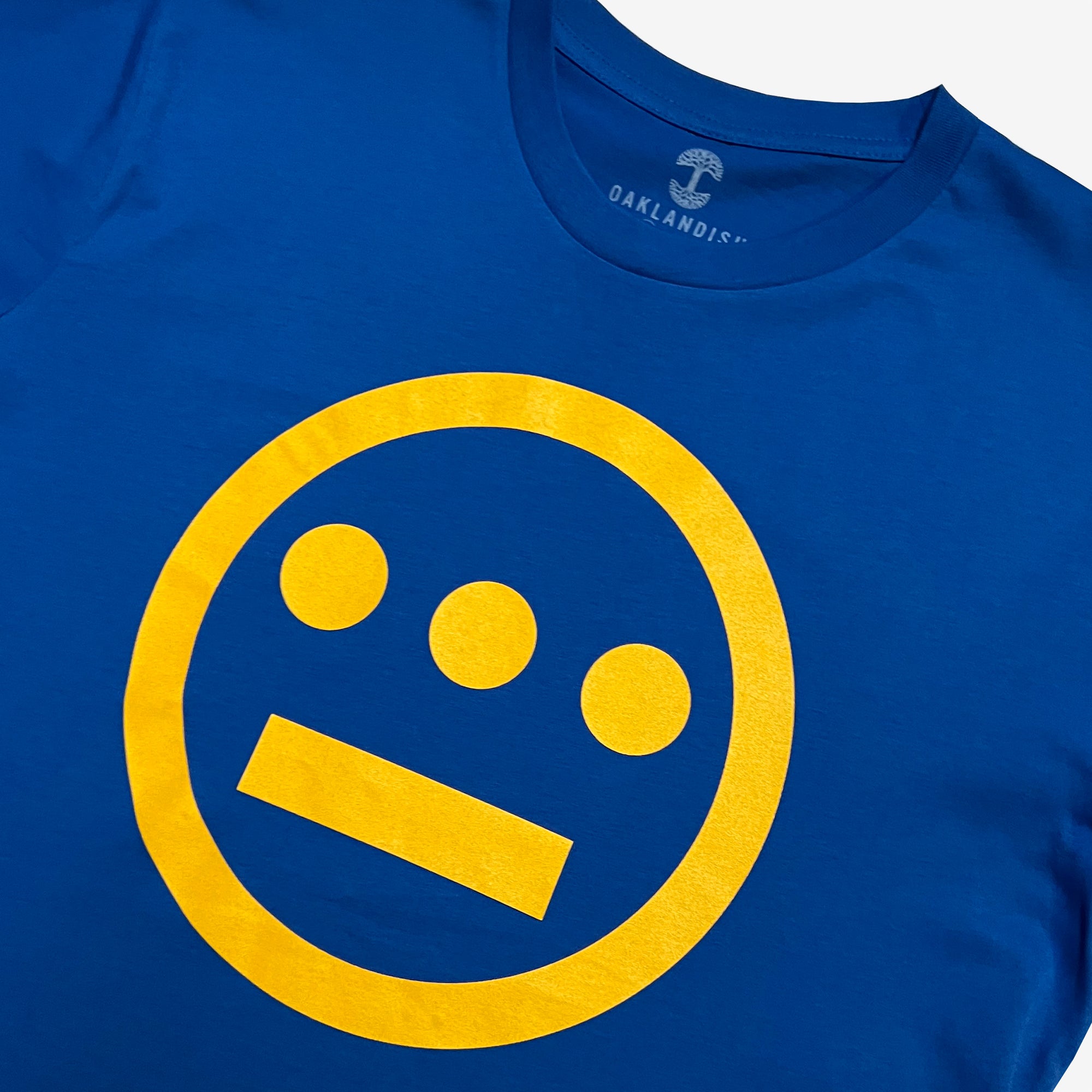 Close up of yellow Hieroglyphics Hip-Hop logo on a royal blue t-shirt.