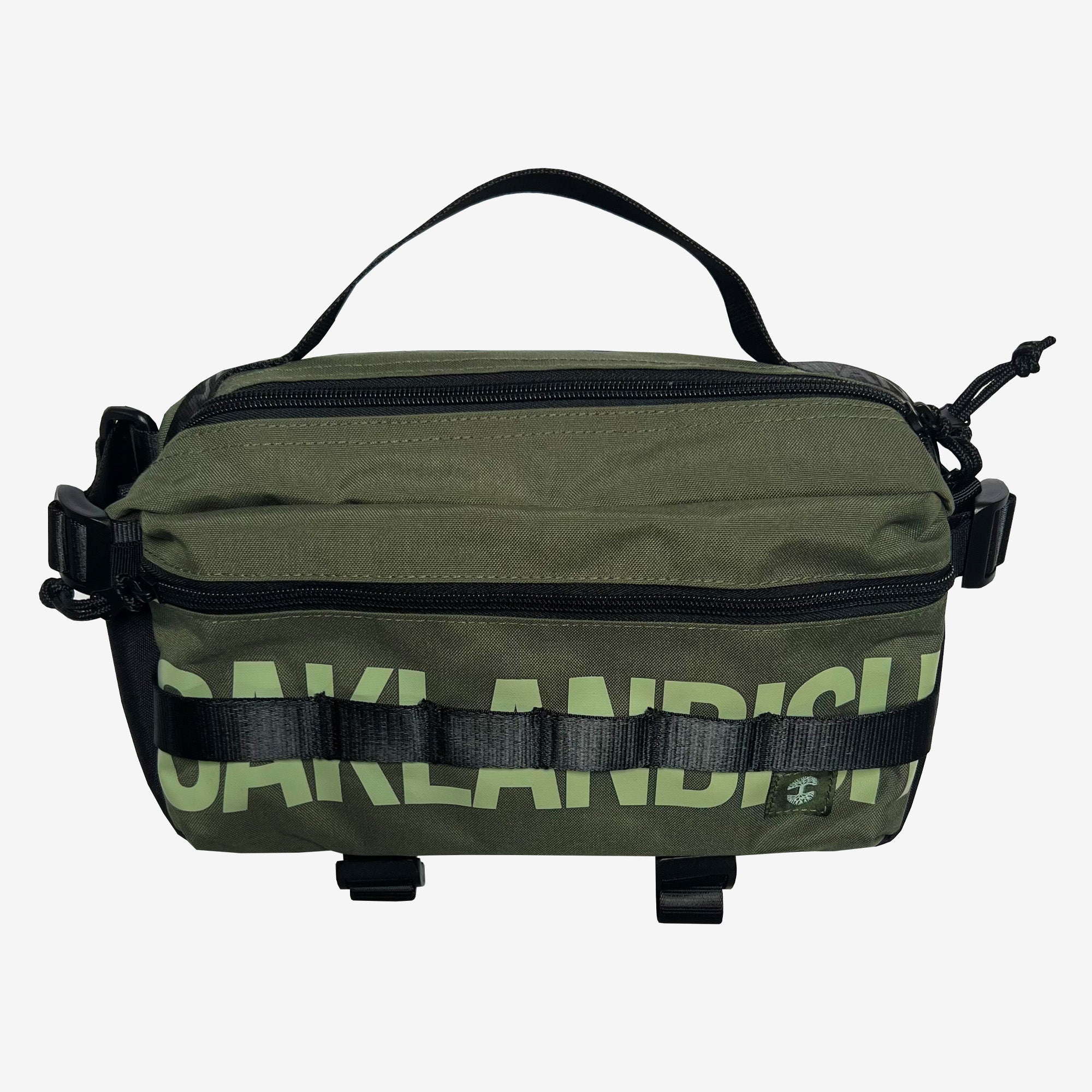 The Oaklandish Hip Bag is a green, rectangular crossbody sling bag with a black top handle and zipper. It features bold, light green text on the front that partially reads "AKLANDISH." The bag includes black strap accents and buckle details on both sides and at the bottom front. Its functional yet stylish design makes it a versatile unisex accessory from the Oaklandish brand.