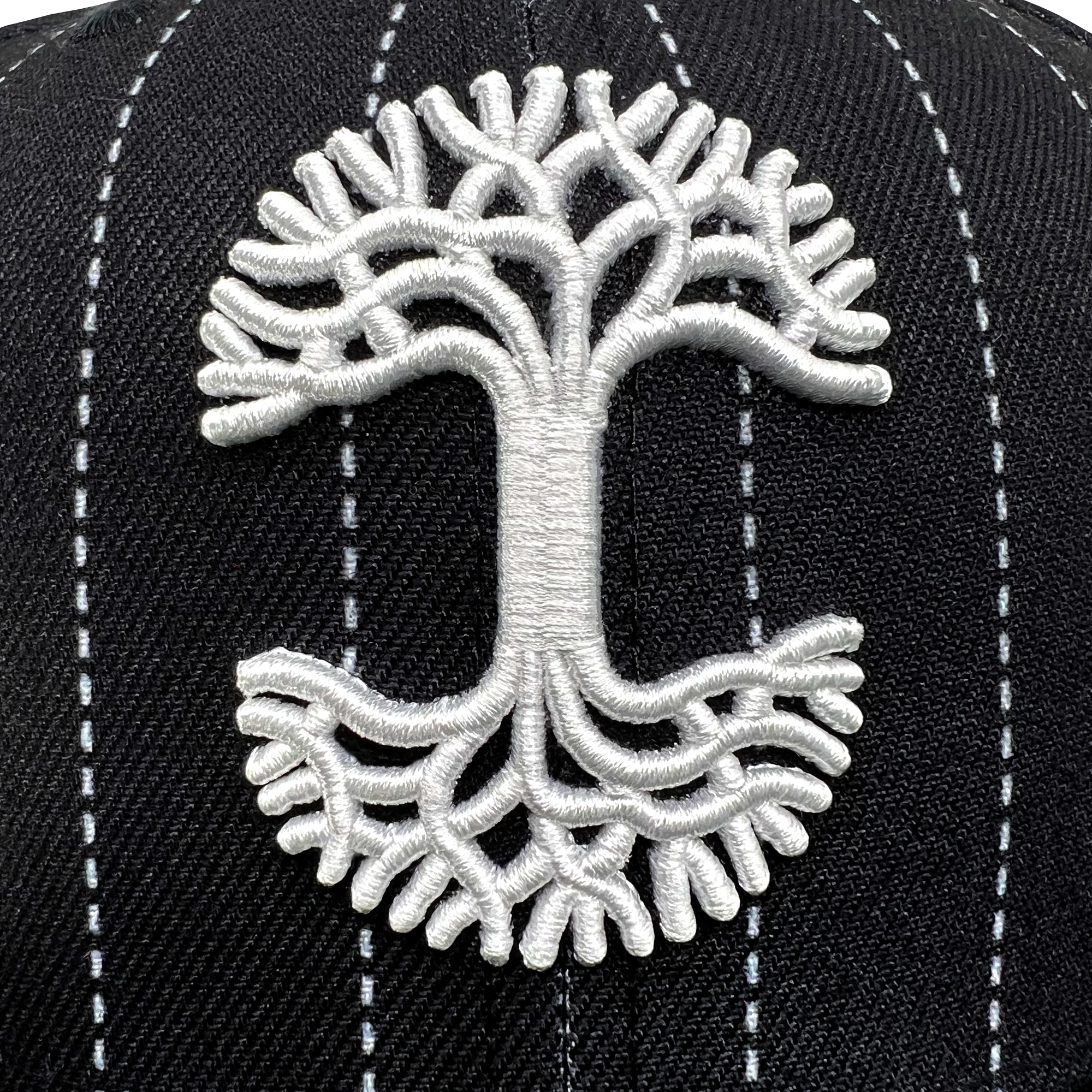 Close-up of white embroidered Oaklandish tree logo on the crown of New Era 59FIFTY black pinstripe fitted cap.
