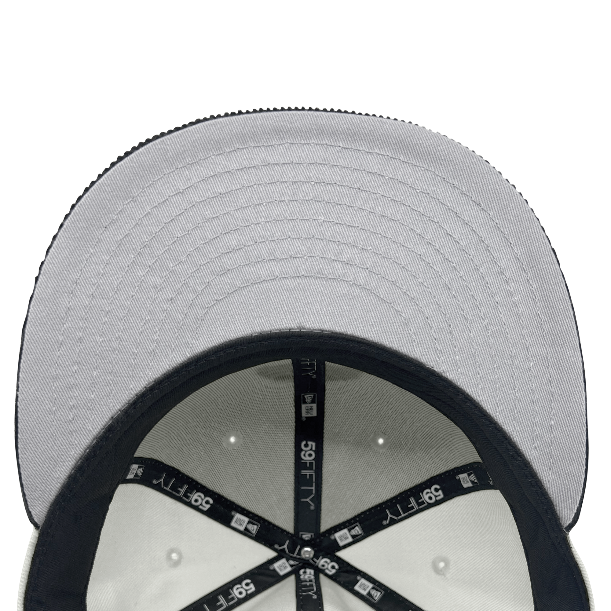 Top-down view of the inside of a New Era X Oaklandish Classic Cord 59FIFTY Fitted Cap. The interior features black inner lining with "59FIFTY" and Oaklandish's logo in white text. The underside of the grey brim has grey stitching, and the size tags are visible on the inside lining.