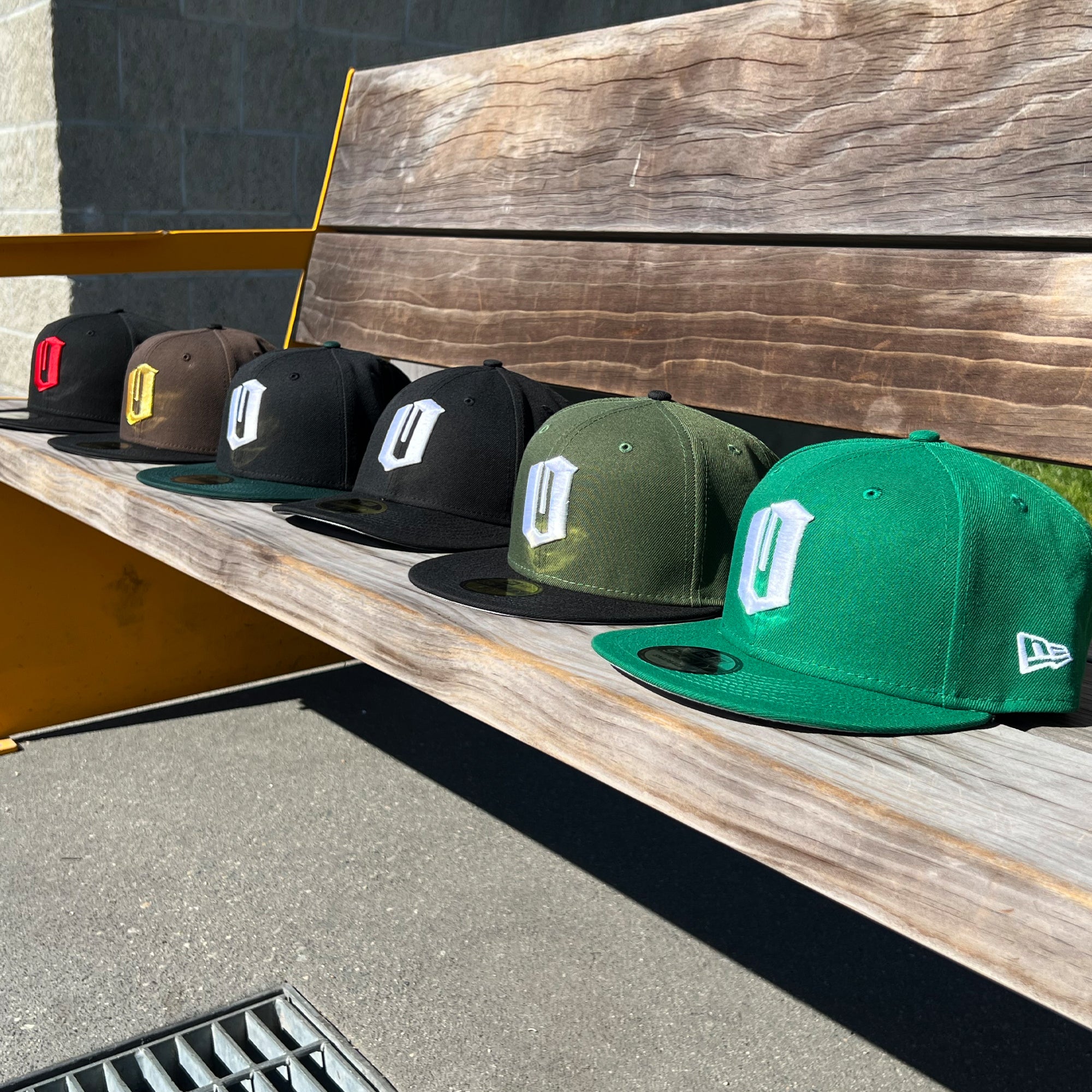 All 6 colorways of New Era Official 9FIFTY Snapback caps with embroidered O for Oakland displayed on an outdoor bench.