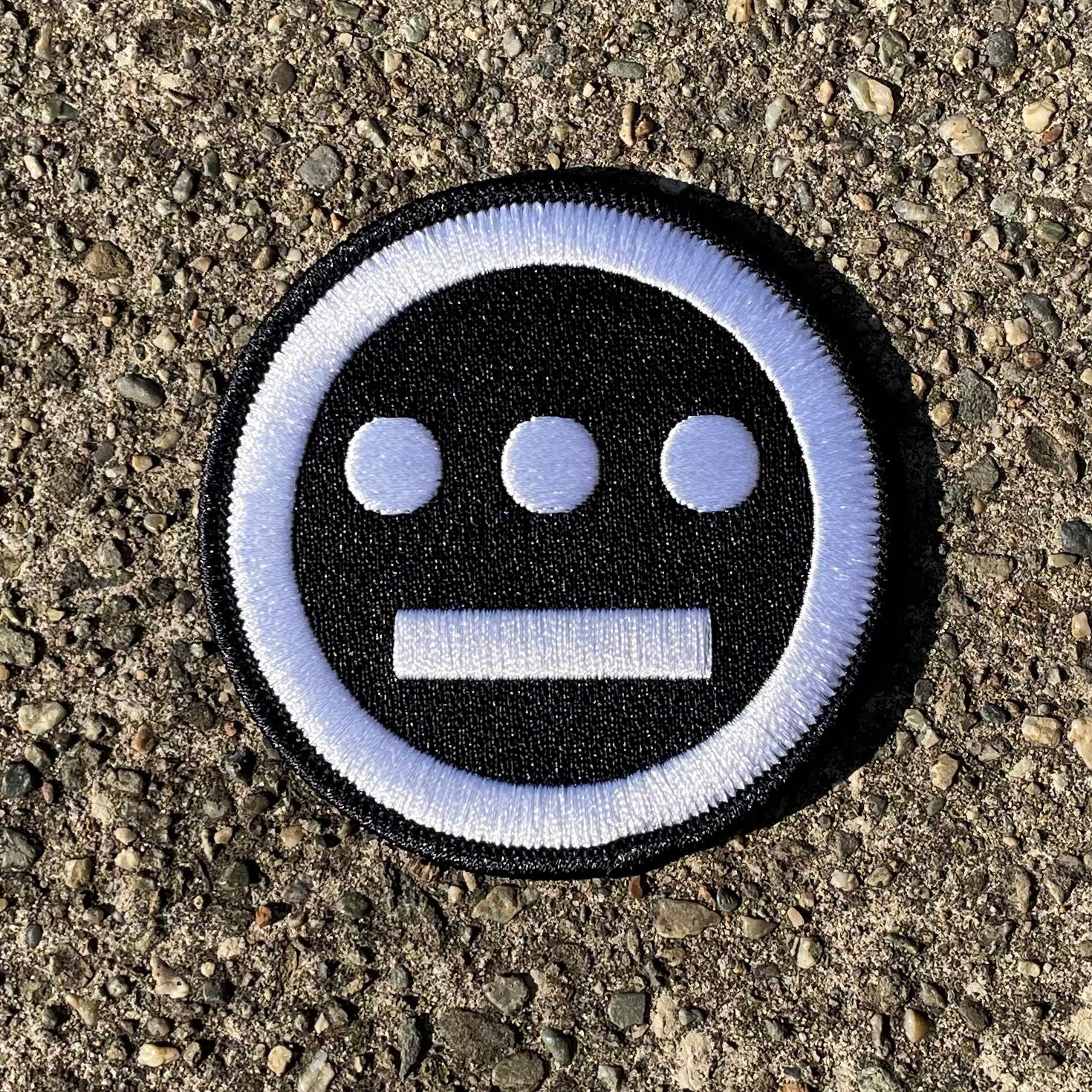  Embroidered patch with black and white Hieroglyphics logo on cement.