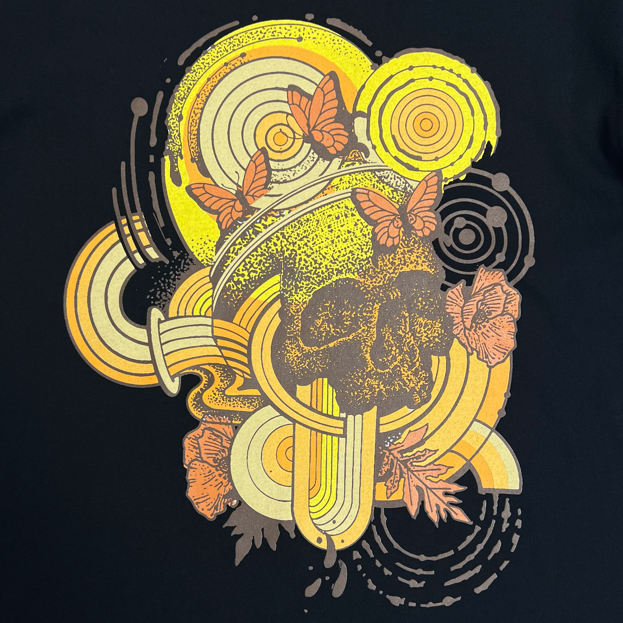 Close-up of swirl design symbolizing rebirth featuring butterflies with a skull at the center on a black cotton t-shirt.