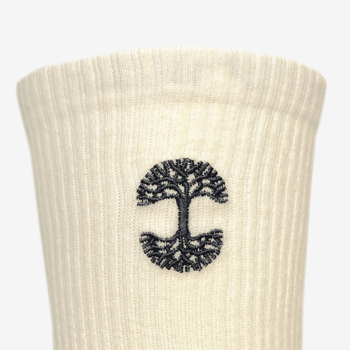 Close up of black embroidered Oaklandish logo at the top of cream men’s crew socks.