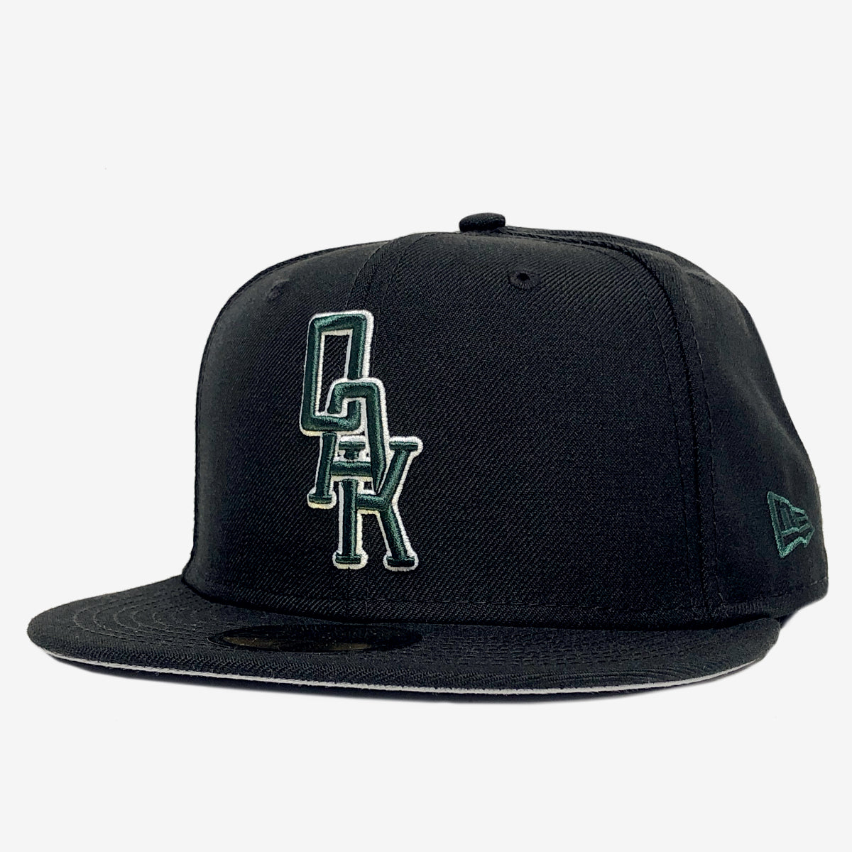A black New Era OAK 59FIFTY Fitted Cap by Oaklandish, featuring a flat brim and an embroidered OAK logo in green and white on the front. The cap has a signature circular sticker on the brim and the New Era logo in green on the side, set against a plain white background.