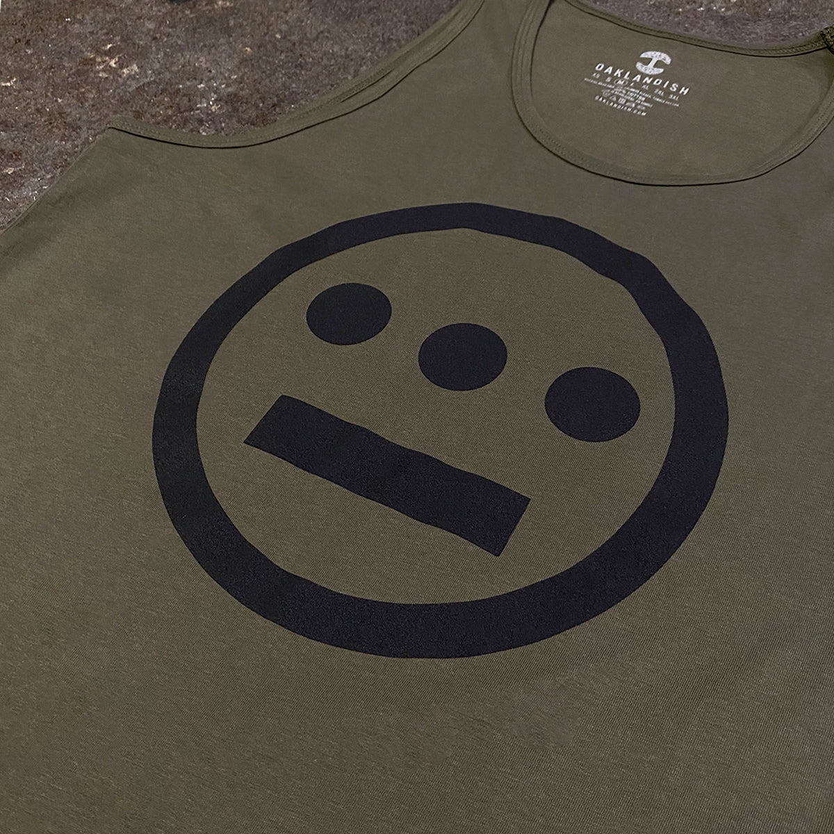 Military green tank top with black Hieroglyphics hip hop logo on the chest on asphalt.