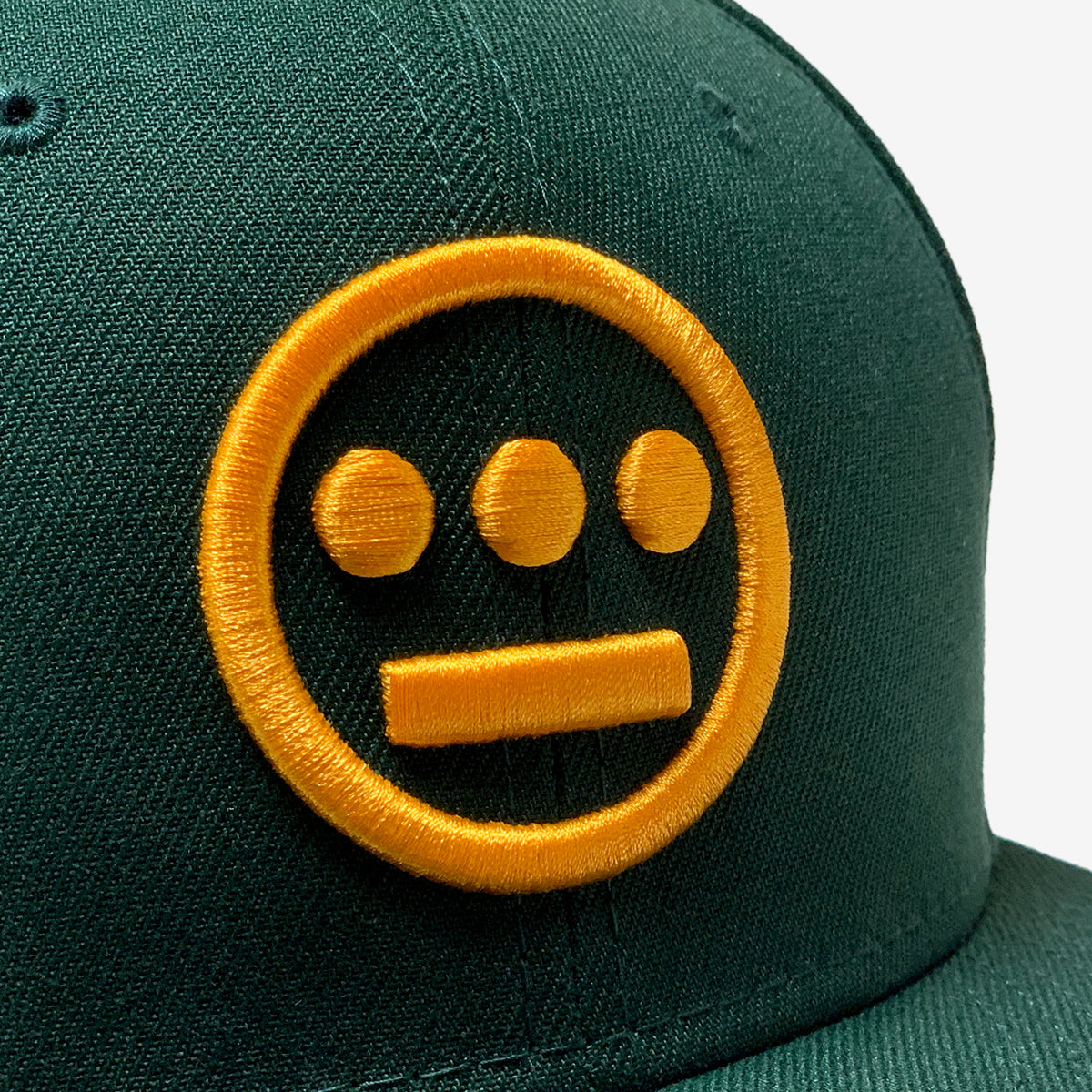 Close-up of gold embroidered Hieroglyphics hip-hop logo on the crown of a New Era cap.