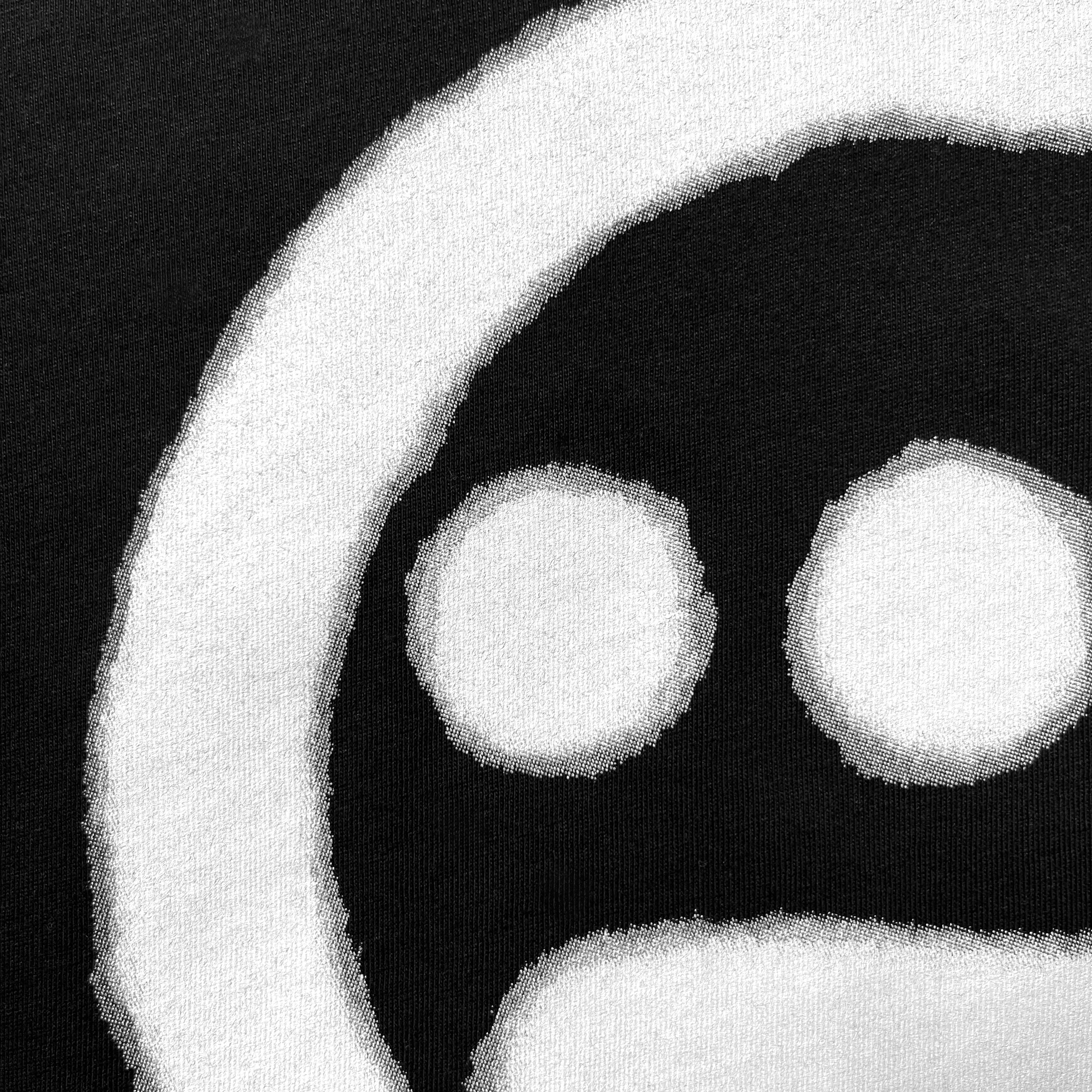Close up of spray-painted Hieroglyphics hip-hop logo on the chest of a black t-shirt.