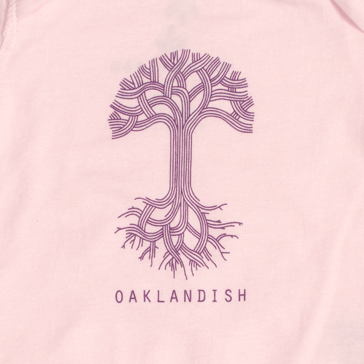 The Infant Oaklandish Classic Logo One-Piece by Oaklandish is made of 100% cotton and showcases a pale pink fabric adorned with an intricate, stylized tree design in purple. The geometric branches and roots mirror each other symmetrically, with "OAKLANDISH" printed below the tree in bold, uppercase letters.