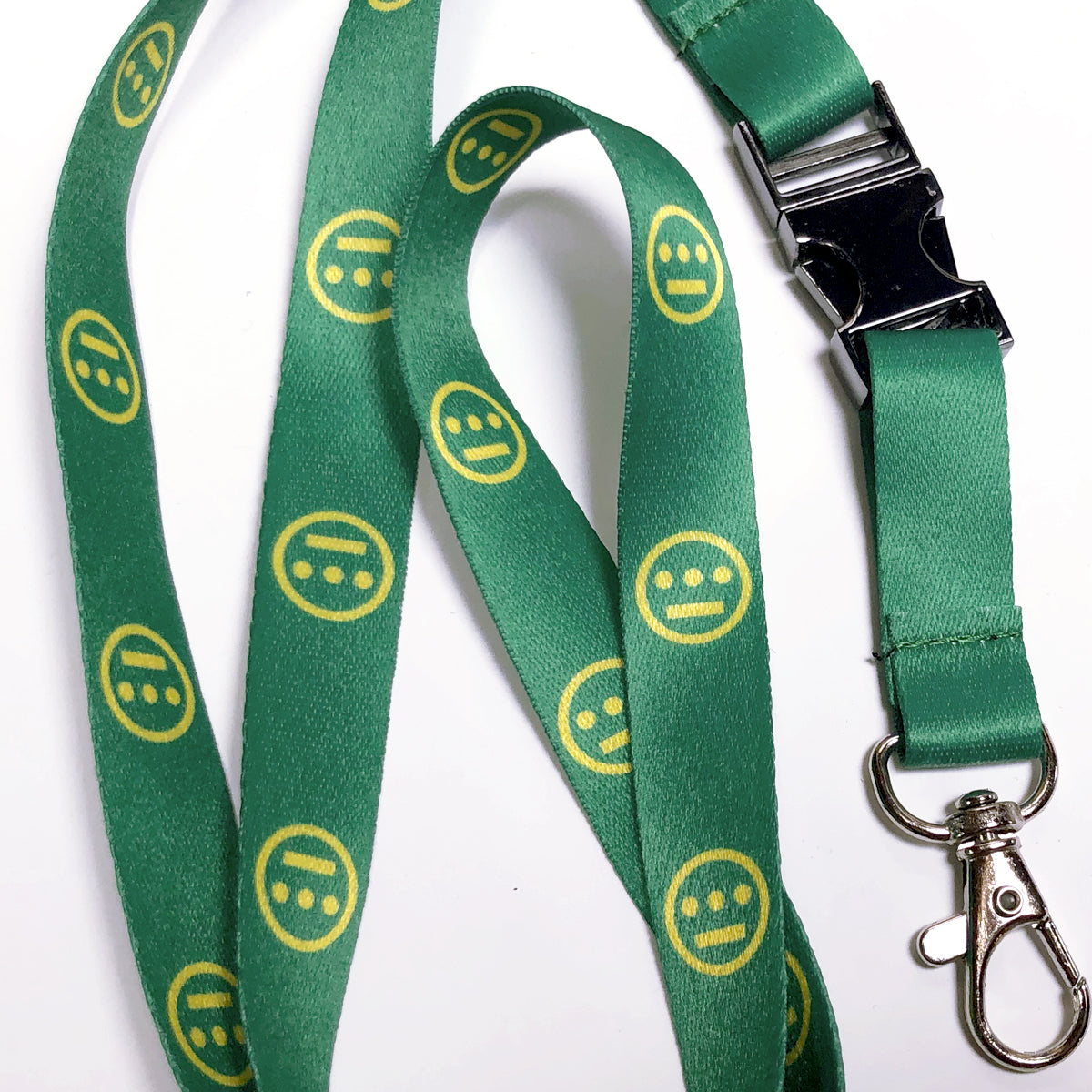 The Hiero VIP Lanyard by Hieroglyphics is a green lanyard adorned with a repeating pattern of yellow, neutral-faced emoji icons that resemble modern hieroglyphics. It features a black plastic quick-release buckle and a metal swivel hook clasp, making it perfect for attaching to your key chain, all set against a white background.