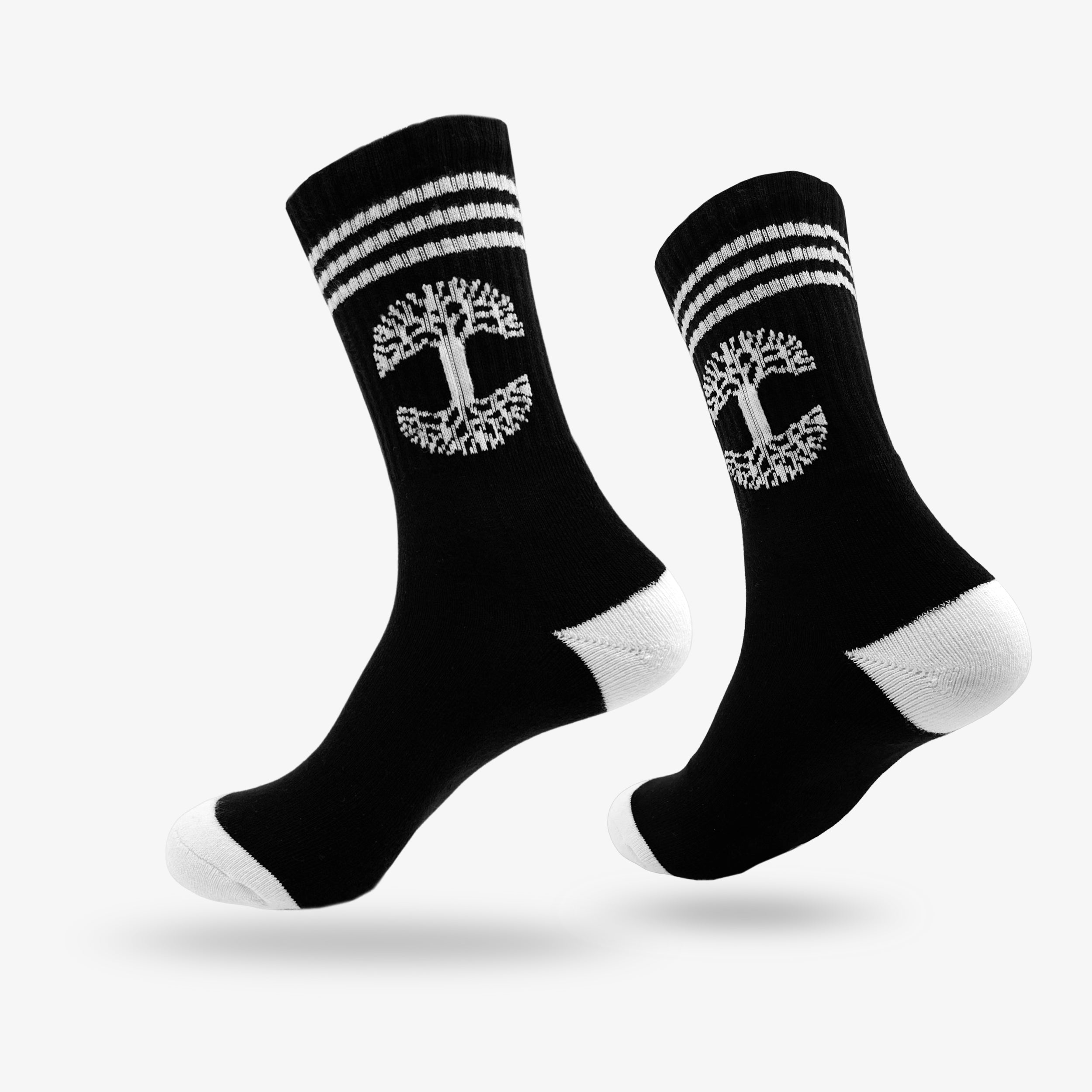 A pair of Retro Classic Socks from Oaklandish, exceptionally comfy in black, featuring a white tree emblem and two horizontal white stripes near the top. The socks have unique white heels and toes, displayed with one sock slightly in front of the other against a plain white background.
