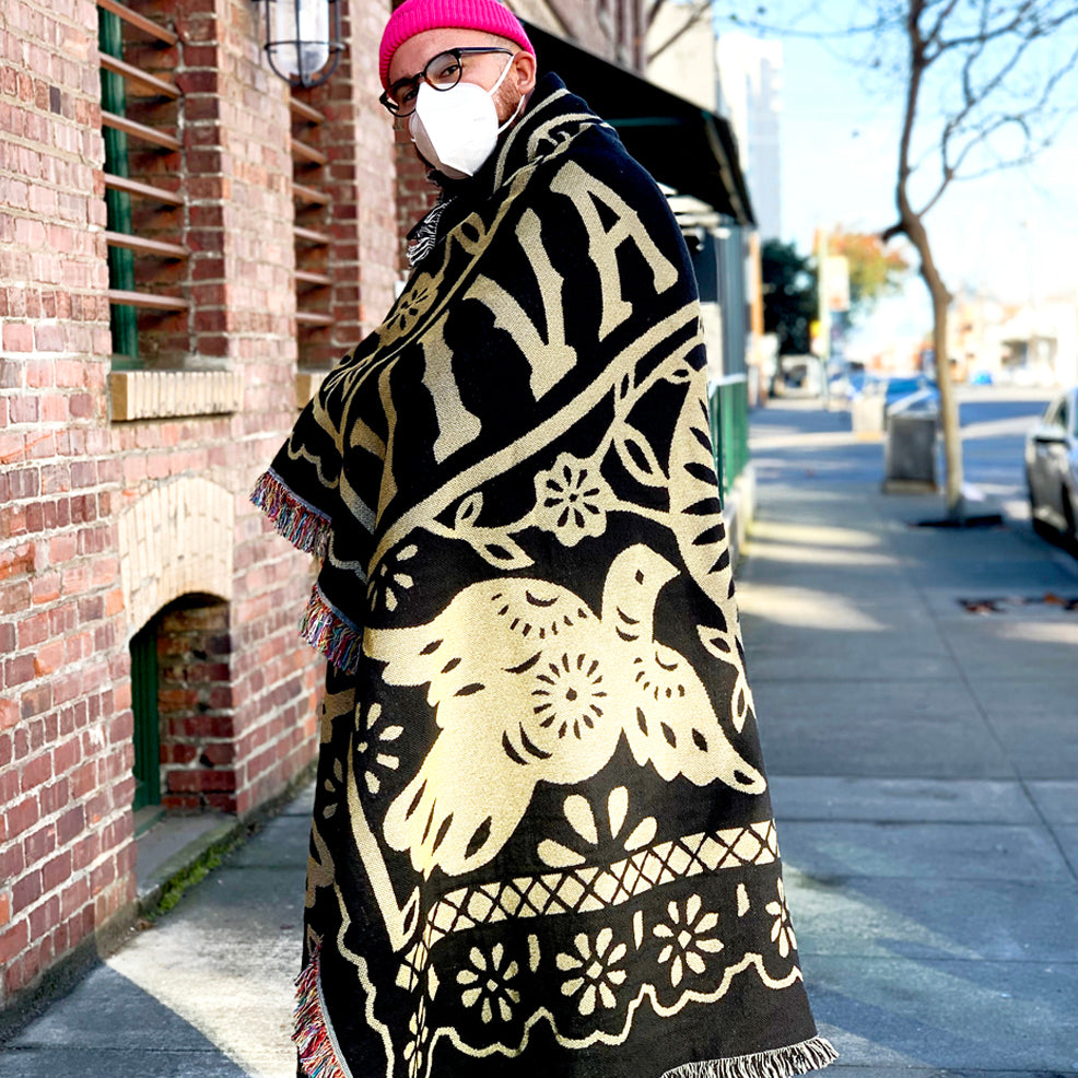 Male model wearing throw blanket wrapped around body outside- viva oakland - black and gold -100% cotton