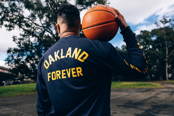 Man wearing Oakland Forever long sleeved tee, holding a basketball.