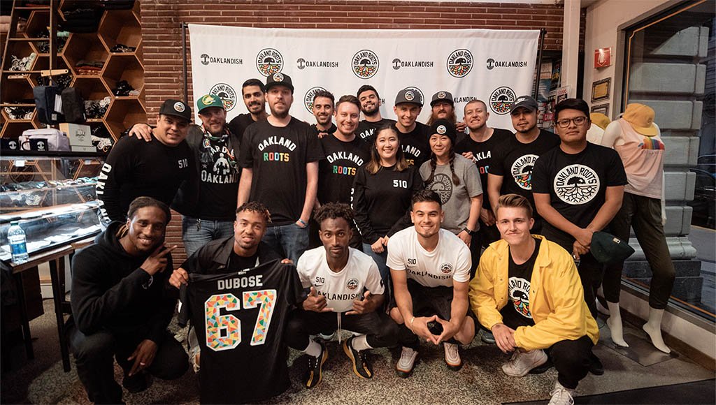 A group of players and staff and fans in front of step and repeat at the Downtown store.