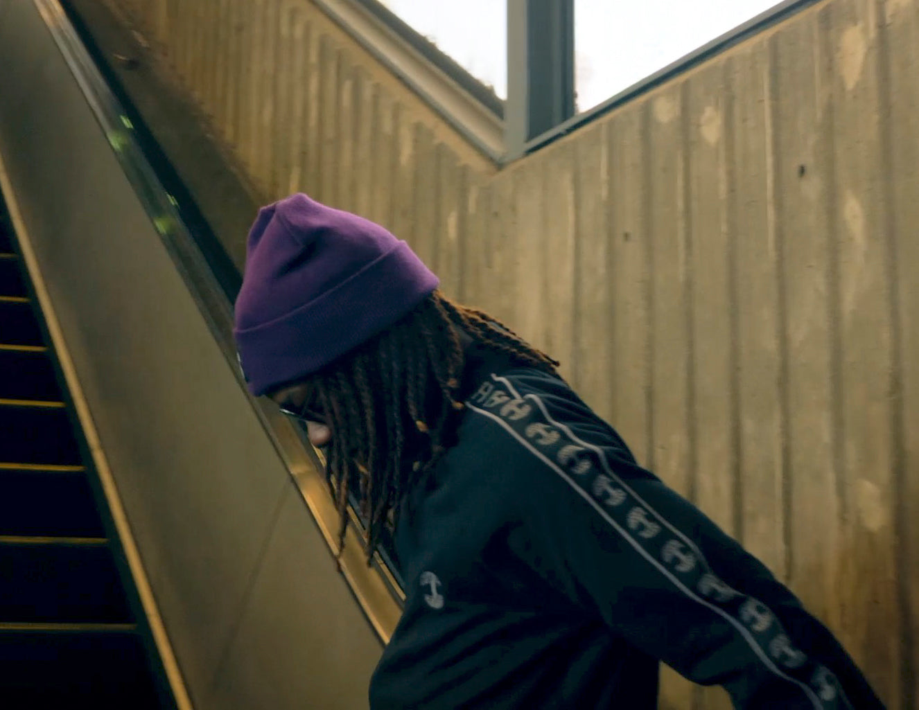 Turf dancer wearing black track jacket and purple beanie.