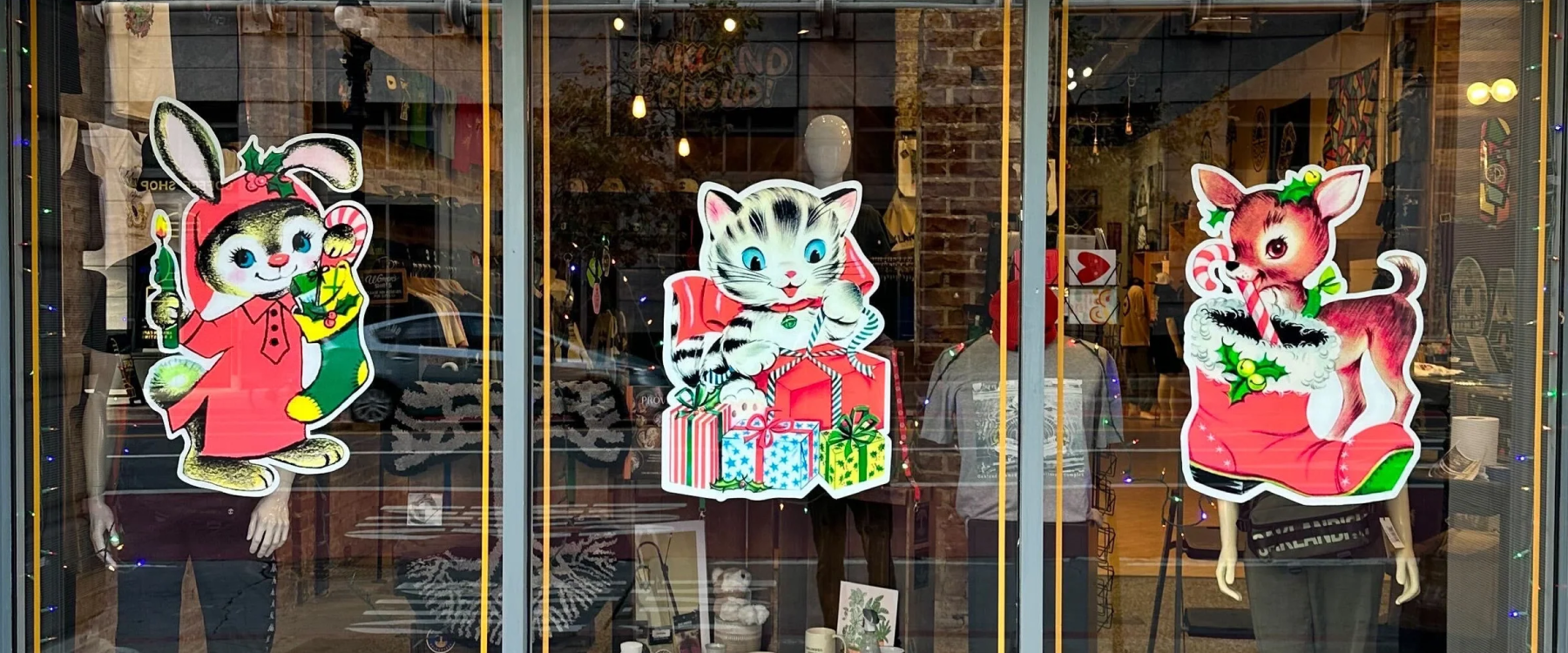 Closeup photo of Oaklandish store window display with holiday themed decals in windows depicting cute retro animals. 