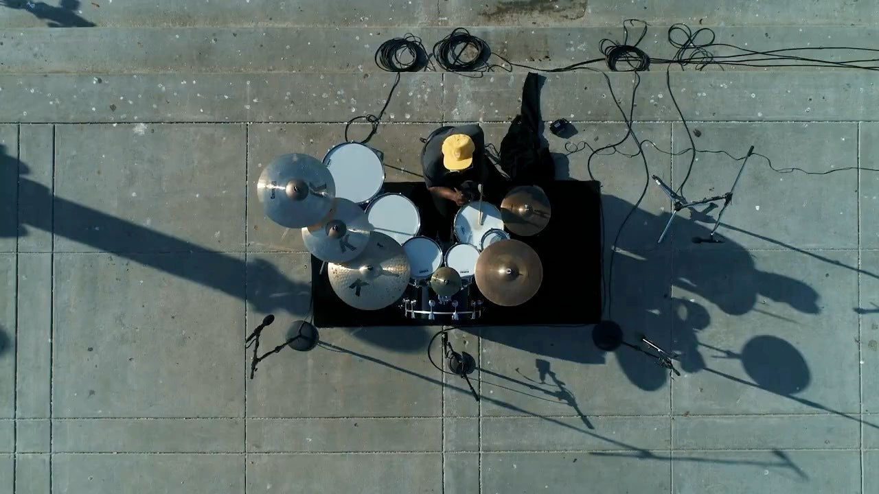 A view from above of Thomas seated in front of his drum kit on the shores of Lake Merritt.
