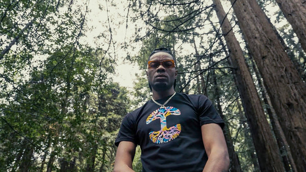 Male model in forest wearing black tee with multicolor tree deign.