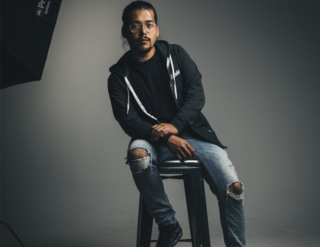 Luis in a studio seated on a barstool, very grey colors.
