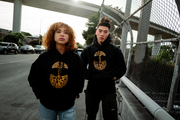 girl and guy wearing Ancestree design on black hoodies, on a freeway overpass