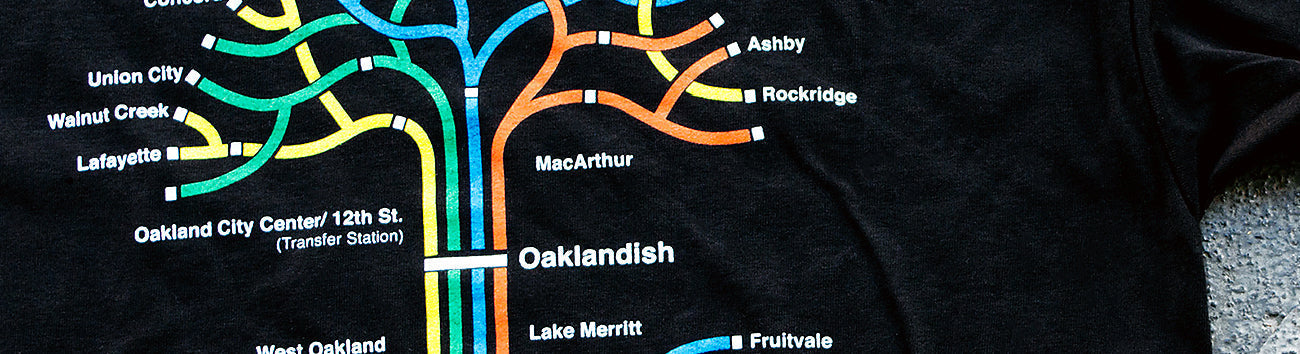 Close up a full-color BART transit map in the shape of the Oaklandish tree logo on a black t-shirt.