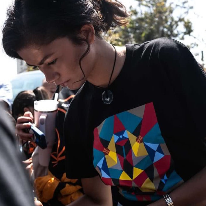 Zendaya wearing an Oaklandish black t-shirt with full-color art by Oakland artist Adian Millett created in collaboration with Project Backboard.