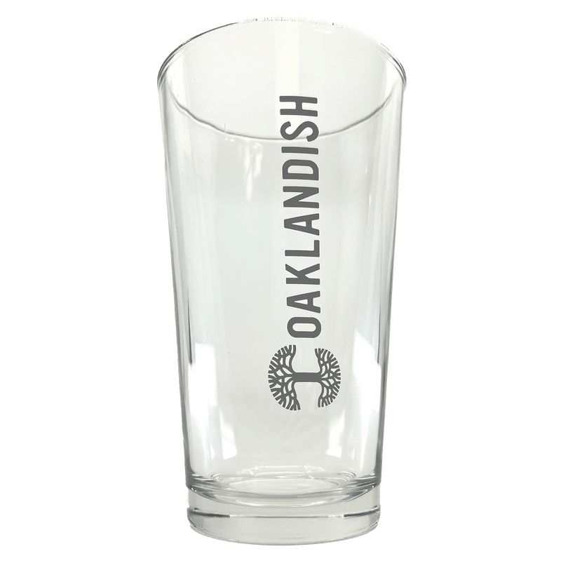 Front view of clear 16 oz glass beer pint glass with dark grey Oaklandish logo and wordmark imprint.