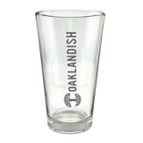 Clear 16 oz glass beer pint glass with dark grey Oaklandish logo and wordmark imprint.