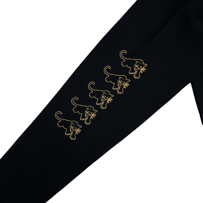 Close-up of gold Black Panther outlines on repeat on the sleeve of a black long-sleeve t-shirt sleeve.