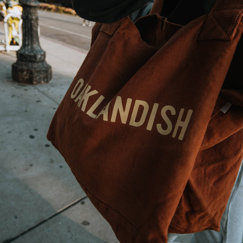 Reverse side of tote with OAKLANDISH block text in cream on ginger tote bag.