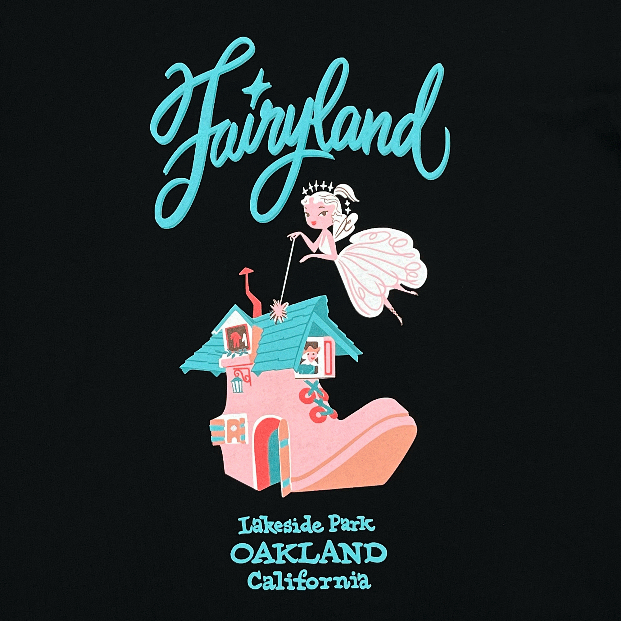 Close-up of retro-style blue and pink Oakland Fairyland graphic on the front center chest of a black women’s cut t-shirt.