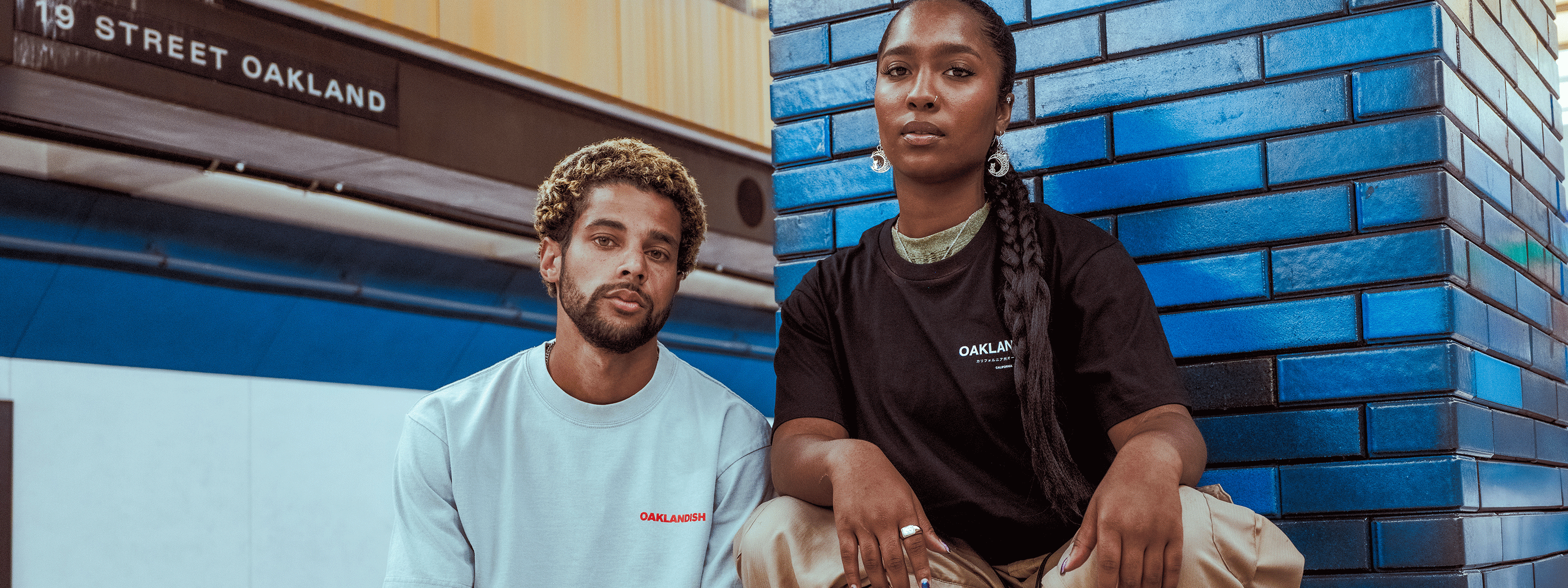 male and female sitting in BART station wearing Oaklandish t-shirts