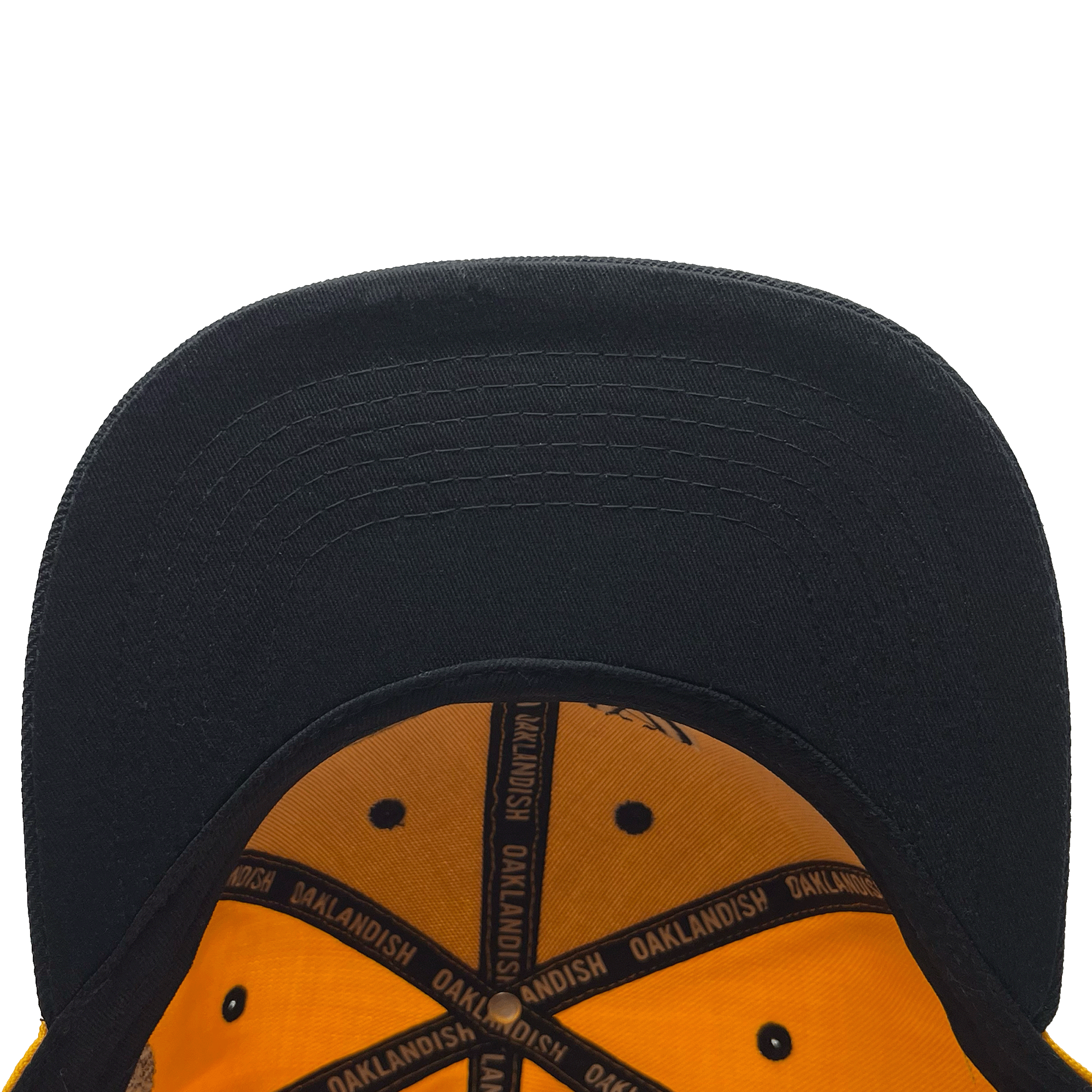 A close-up view of the underside of an OAK Block Snapback by Oaklandish shows a black brim with an orange interior featuring black trim. The word "OAKLANDISH" is repeatedly printed in yellow along the black seams.