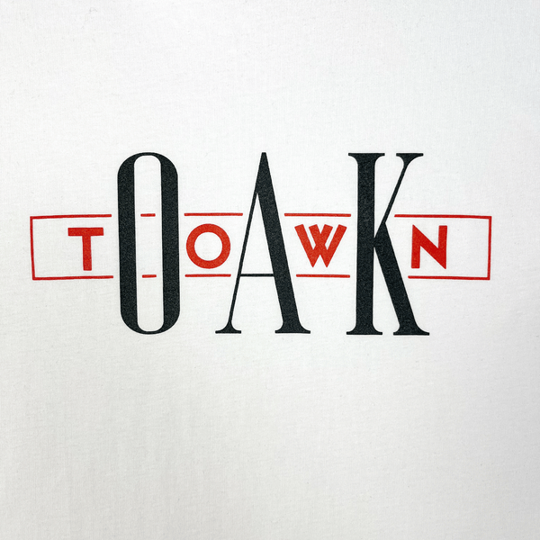 Close up image of women's black t-shirt with OakTown printed at center in red and white ink.
