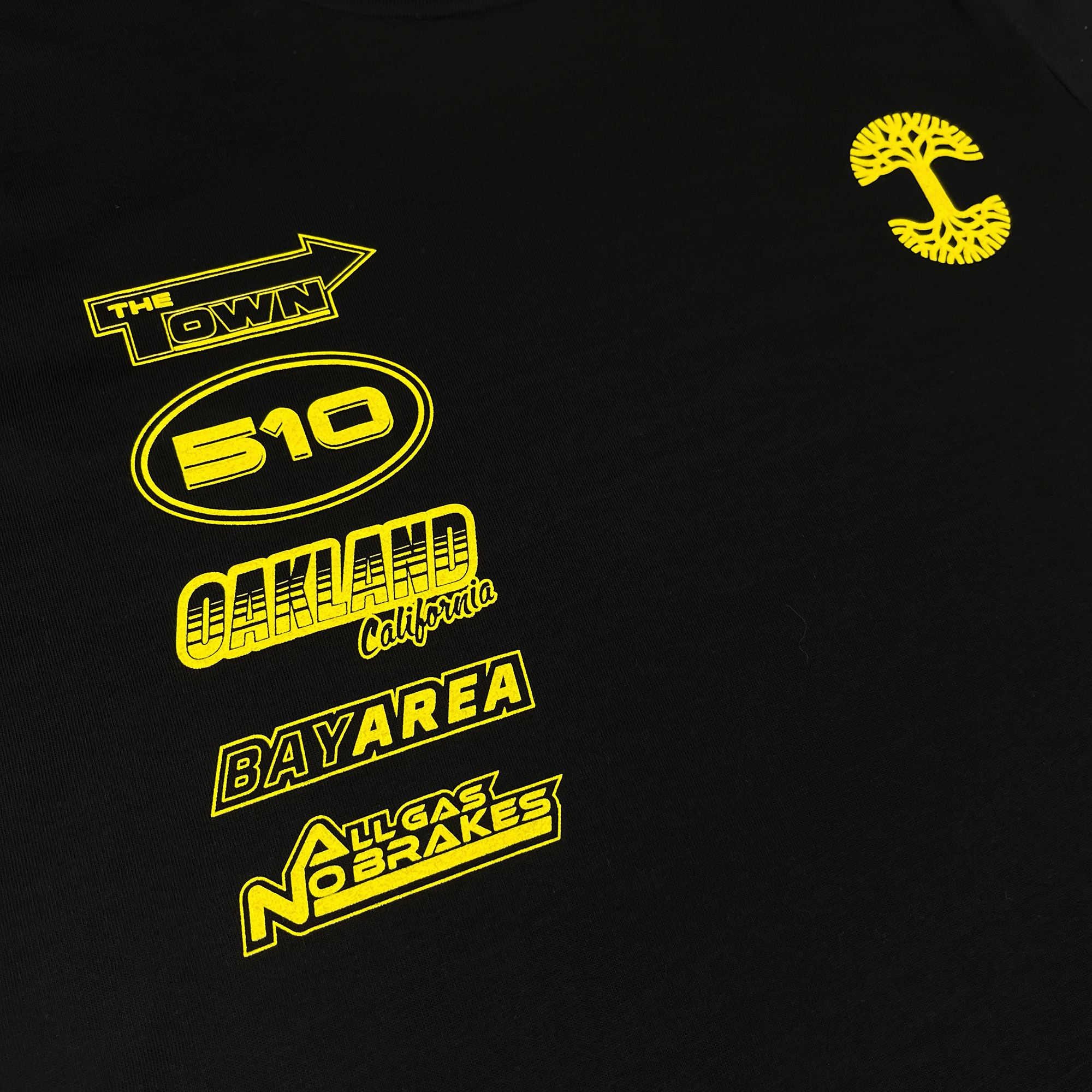 Angled close up image of  black long sleeve t-shirt with yellow racecar-inspired design on front and sleeves.