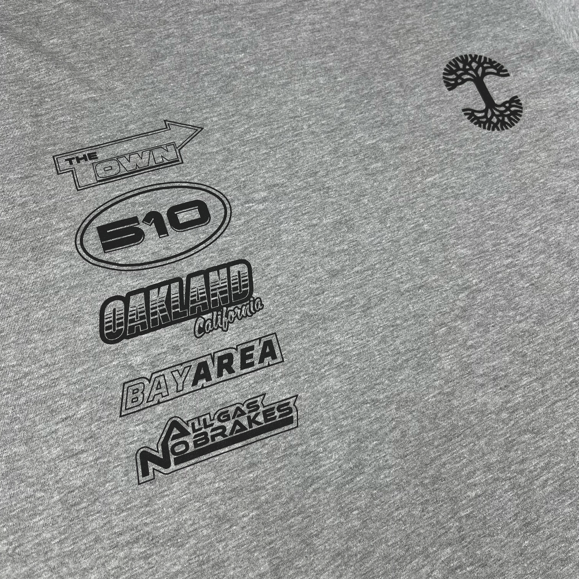 Angled close-up of black race car-inspired design and Oaklandish tree logo on grey long-sleeved t-shirt.