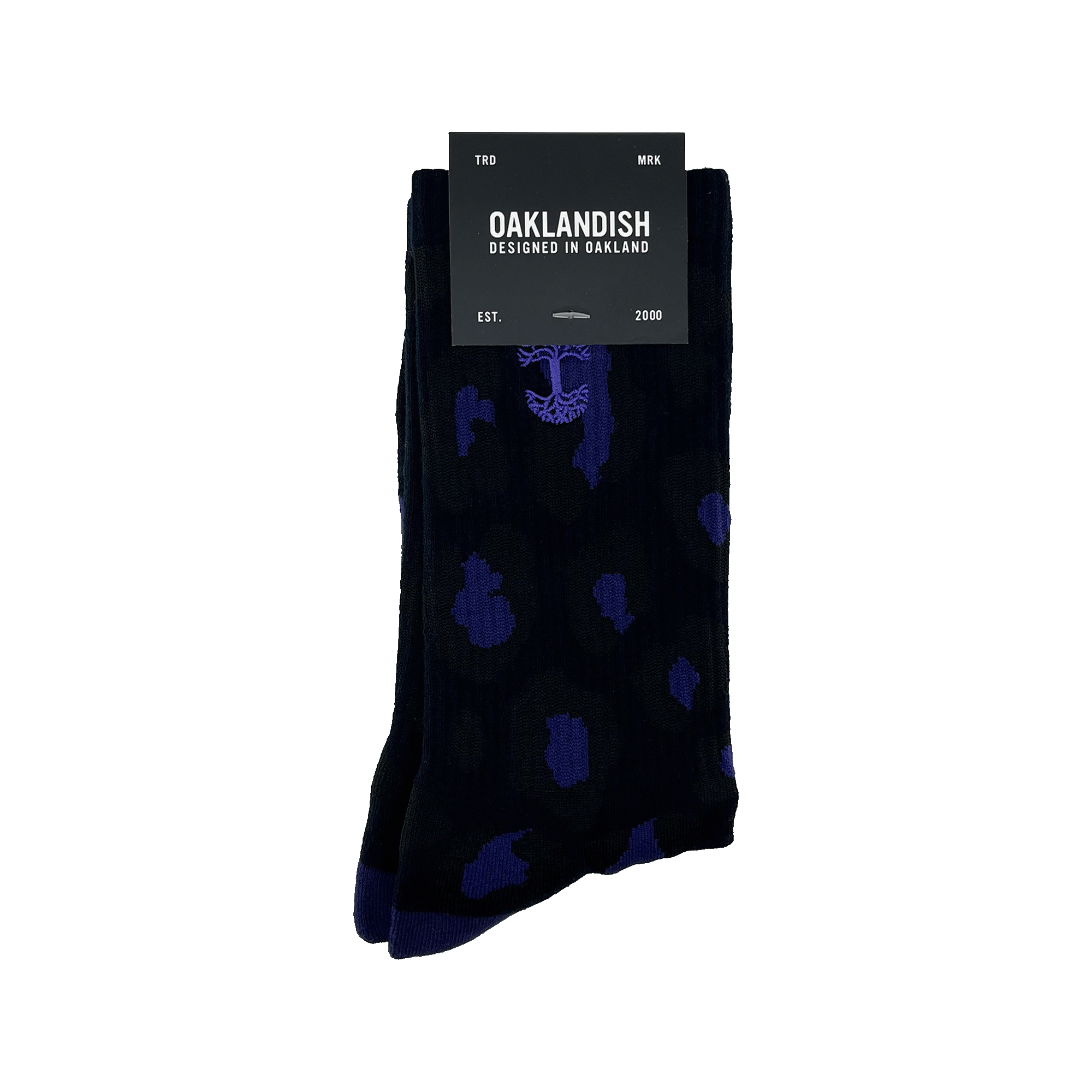 A pair of Panther Socks featuring black crew length with blue polka dot and tree designs, packaged with a black label. The label reads "OAKLANDISH" with "DESIGNED IN OAKLAND" underneath. Additional text includes "TRD MRK" at the top and "EST. 2000" at the bottom. These Oaklandish logo socks are one size fits most.