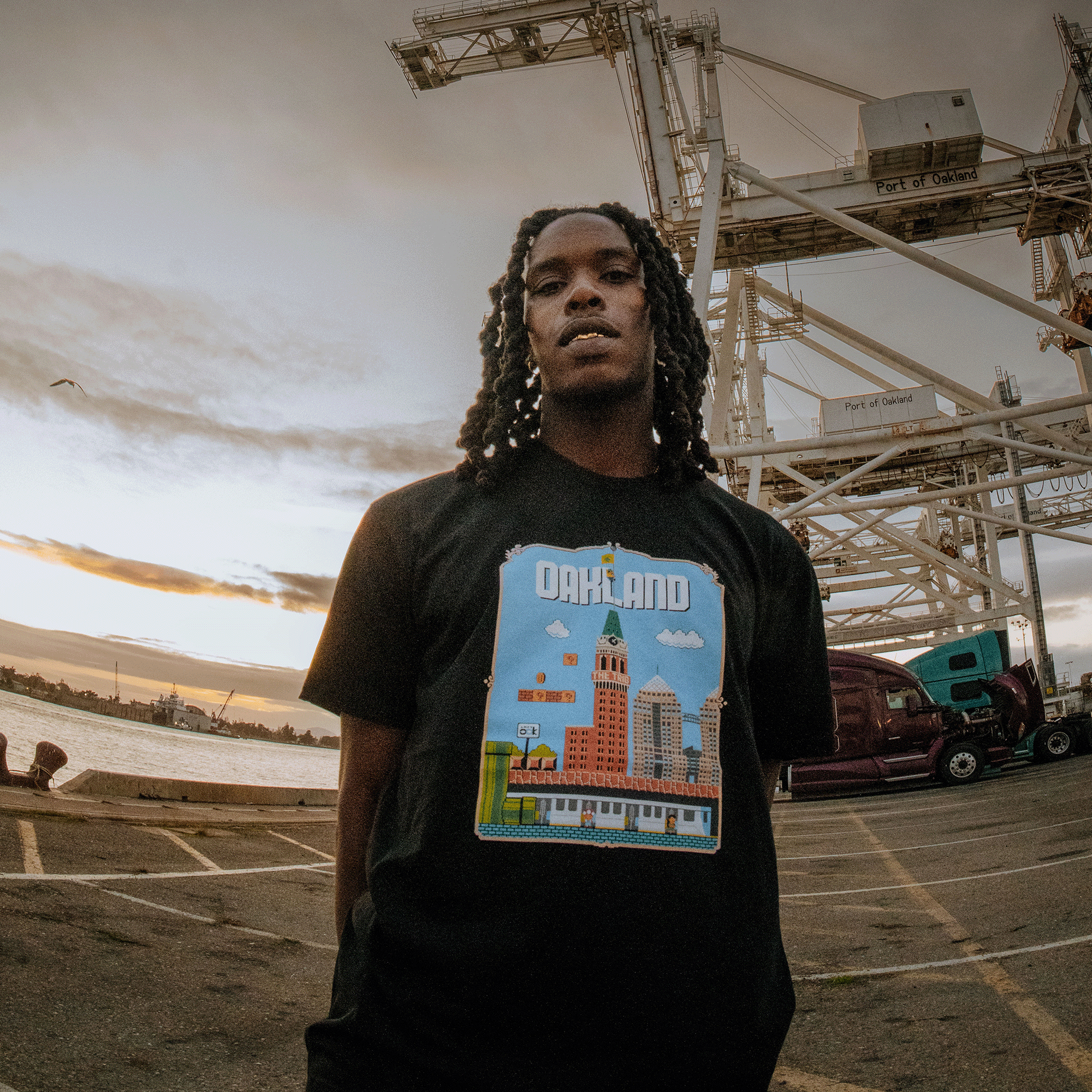 Male model wearing Black t-shirt with Super Mario style graphic with Oakland cityscape.