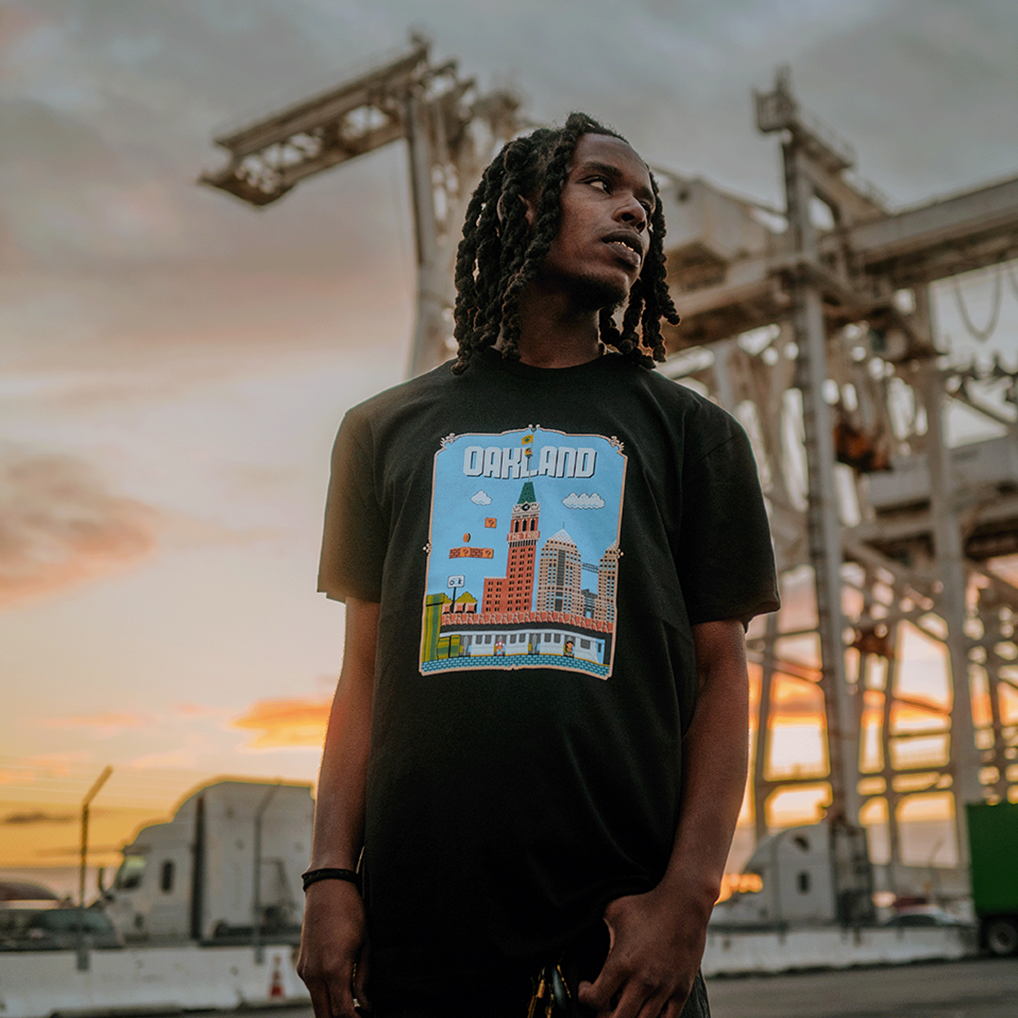 Male model wearing black t-shirt with Super Mario style graphic with Oakland cityscape.