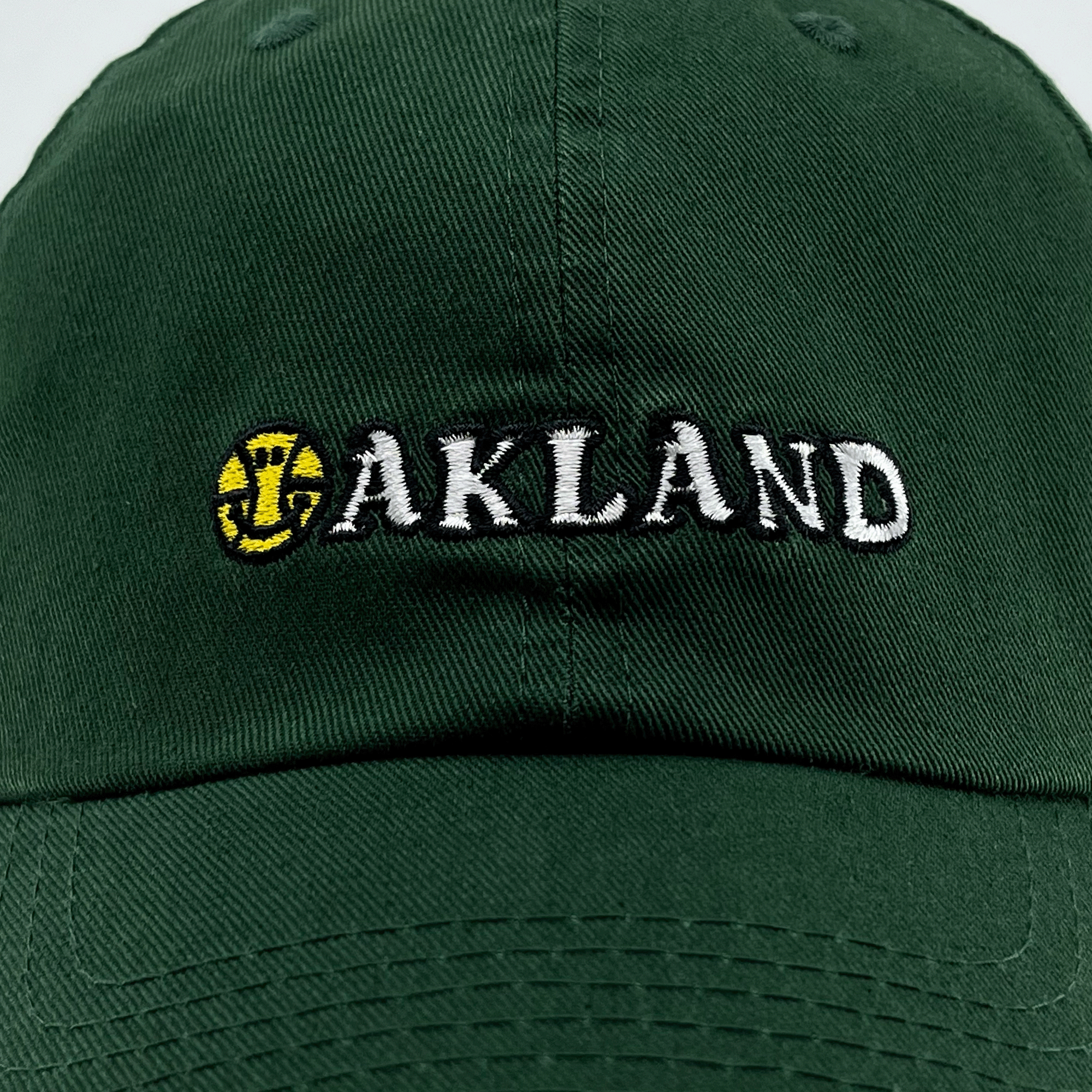 Close-up front view of green Oakland Dad Hat, with embroidered wordmark design by Dustin O. Canalin (DOC).
