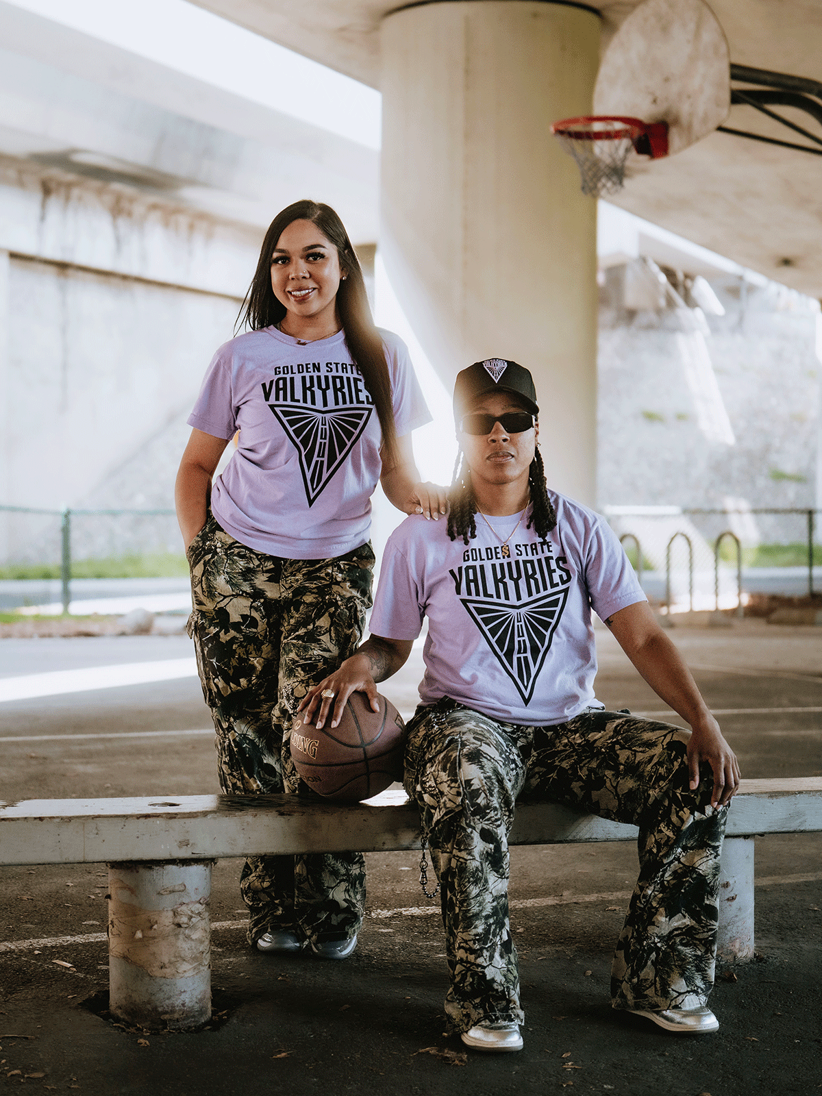 two females at basketball court wearing purple Valkyries t-shirts and camouflage pants 