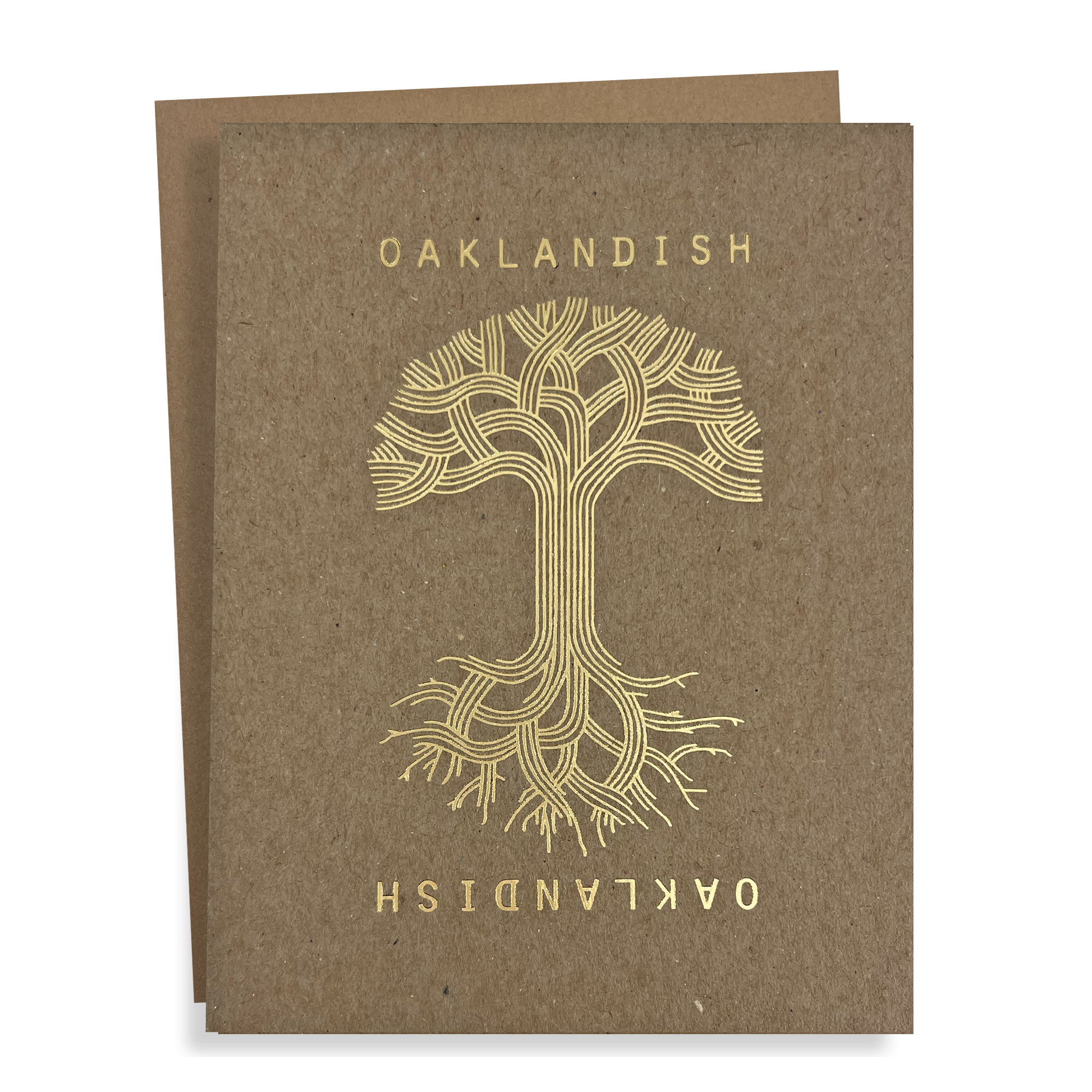 The Oaklandish Classic Logo Card by Never Elsewhere, printed on brown kraft paper, showcases a gold, stylized tree with intricate branching patterns. The word "OAKLANDISH" appears in metallic gold foil at both the top and bottom, with the bottom text inverted. Another identical card is partially visible behind the front card.