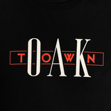 Close-up of Oak and Town printed in red and white ink on a black t-shirt.