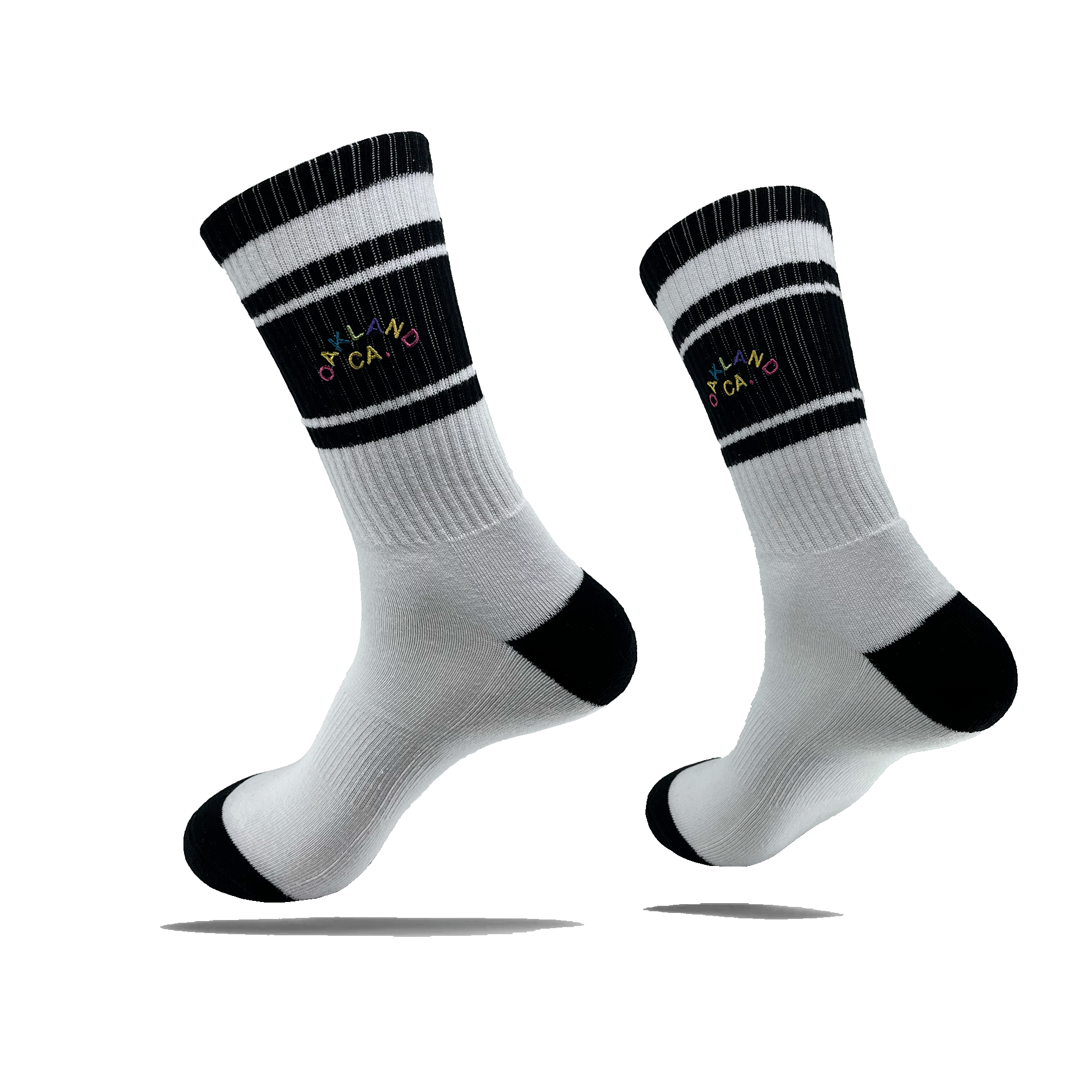 Side view of a pair of white crew socks with black stripes on the calf, black heel and toe, and full-color OAKLAND CALIFORNIA wordmark on the side calf.