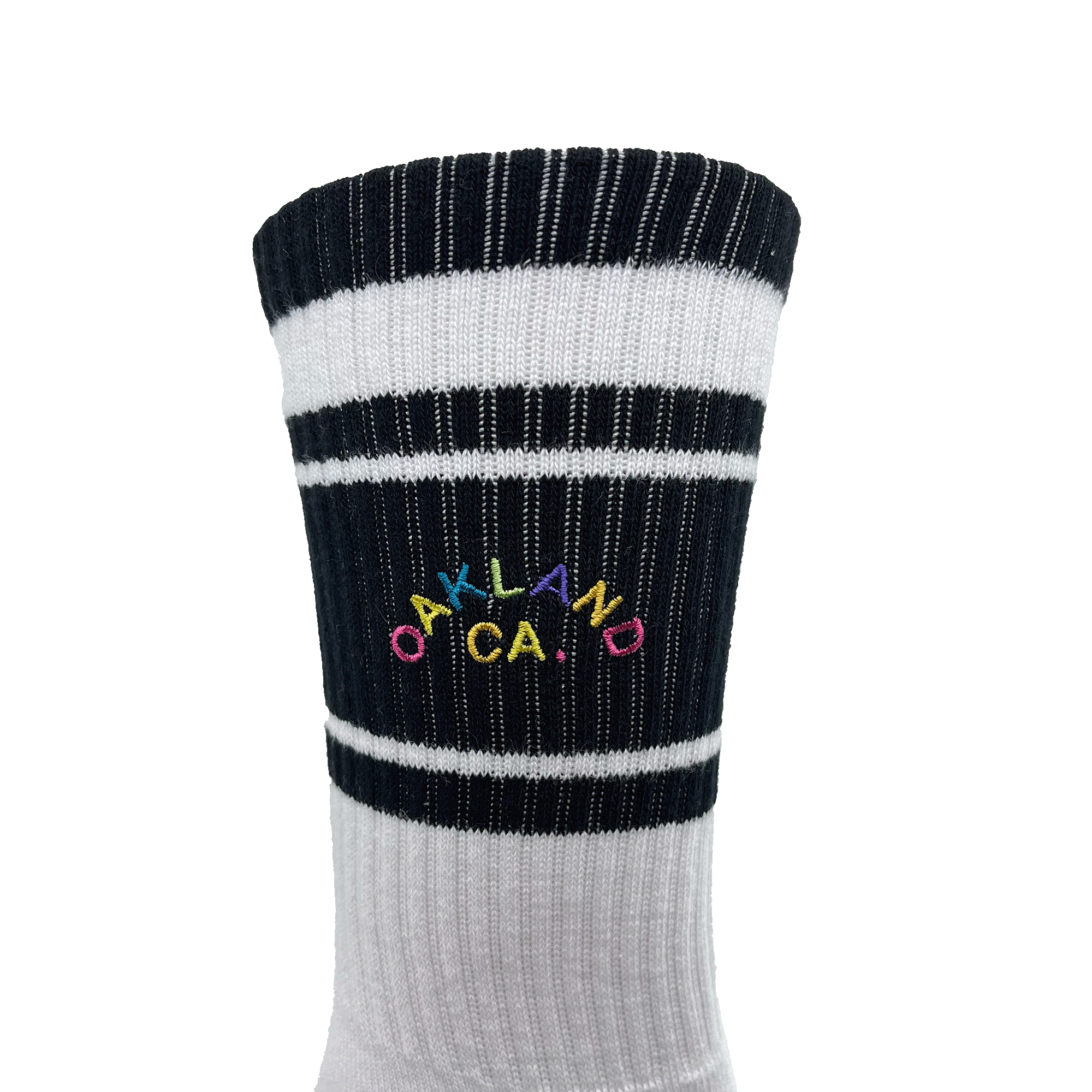 Detailed close-up of full-color OAKLAND CALIFORNIA wordmark on the side calf of a black and white crew sock.